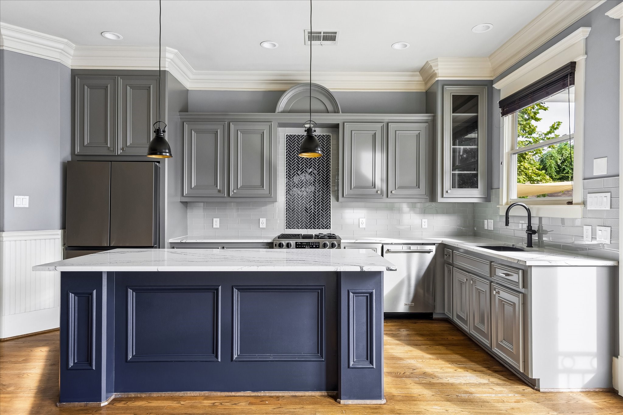 A distinctive herringbone tile inset draws the eye to the range, framed by richly detailed cabinetry. A distinctive herringbone tile inset draws the eye to the range, framed by richly detailed cabinetry.