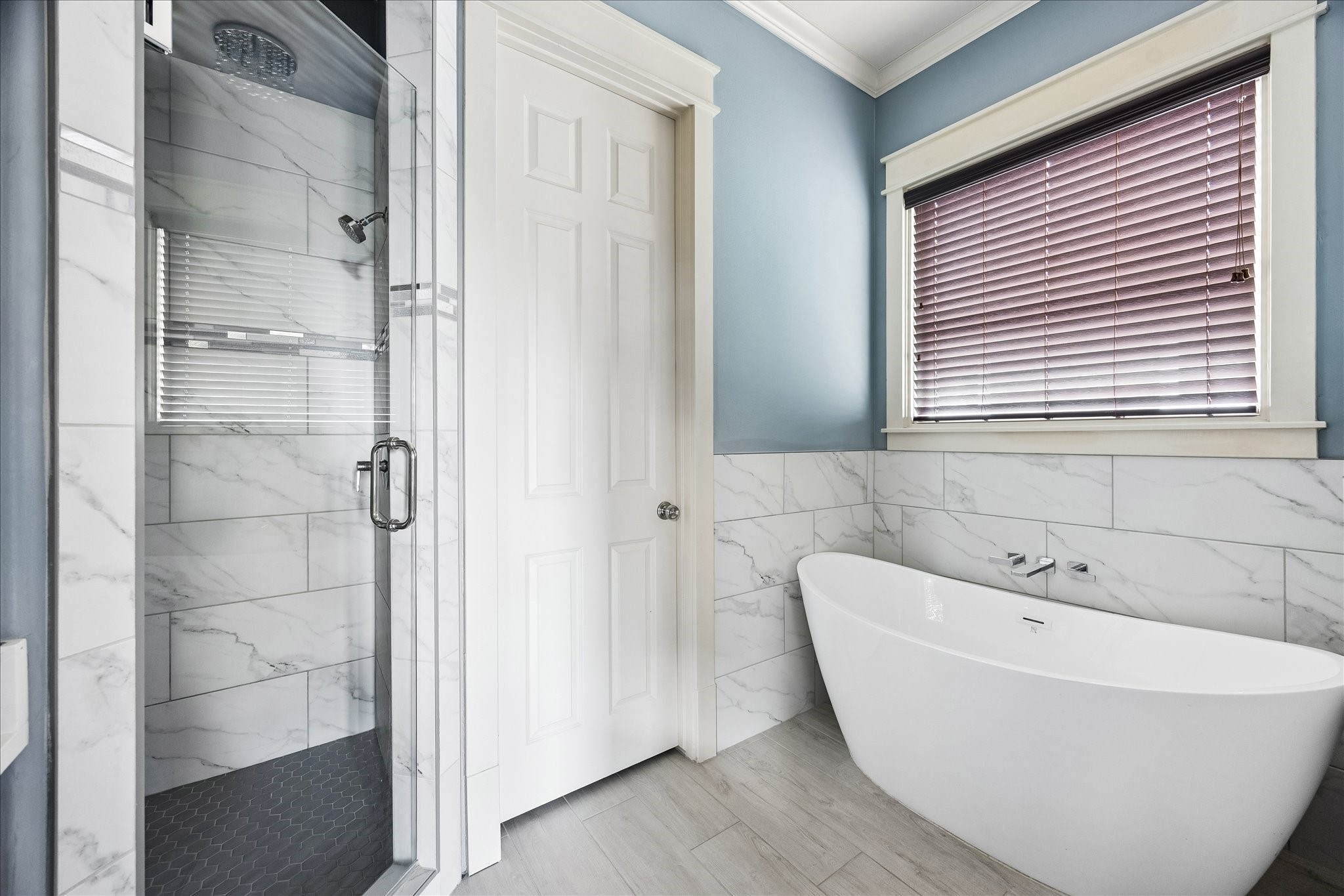 Tile surrounds a freestanding soaking tub and separate glass-enclosed shower, creating a beautifully cohesive design.