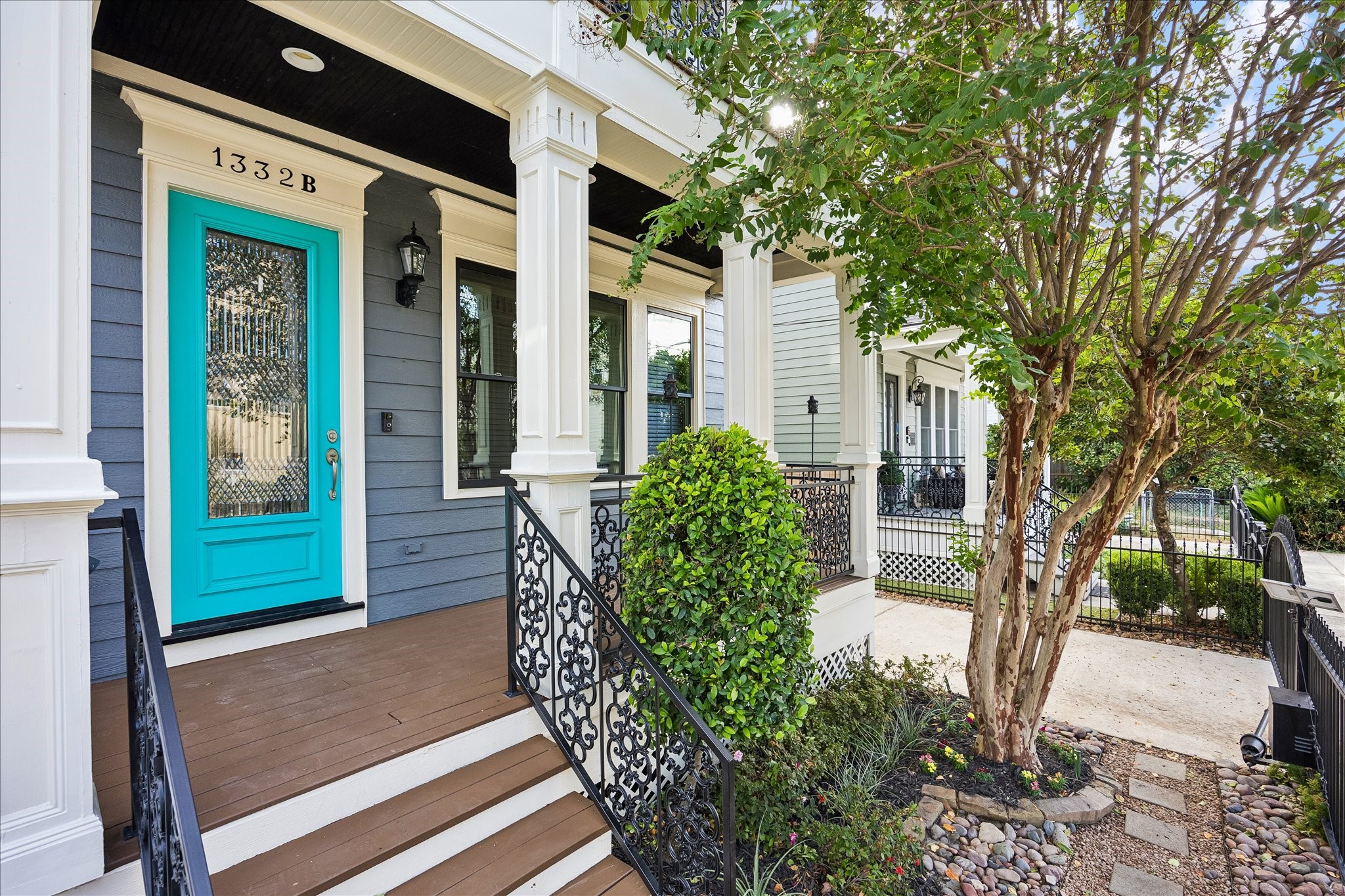 A vibrant turquoise entry door adds a playful touch to the classic columns, intricate iron railings, and welcoming front porch. A vibrant turquoise entry door adds a playful touch to the classic columns, intricate iron railings, and welcoming front porch.