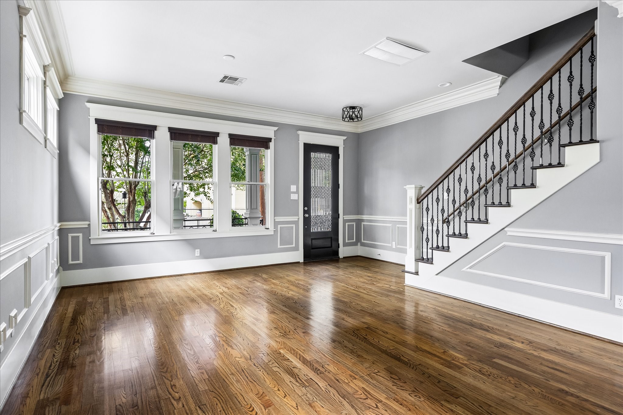 A welcoming view of the front living room highlights the graceful staircase, intricate ironwork, and beautifully detailed millwork throughout. A welcoming view of the front living room highlights the graceful staircase, intricate ironwork, and beautifully detailed millwork throughout.