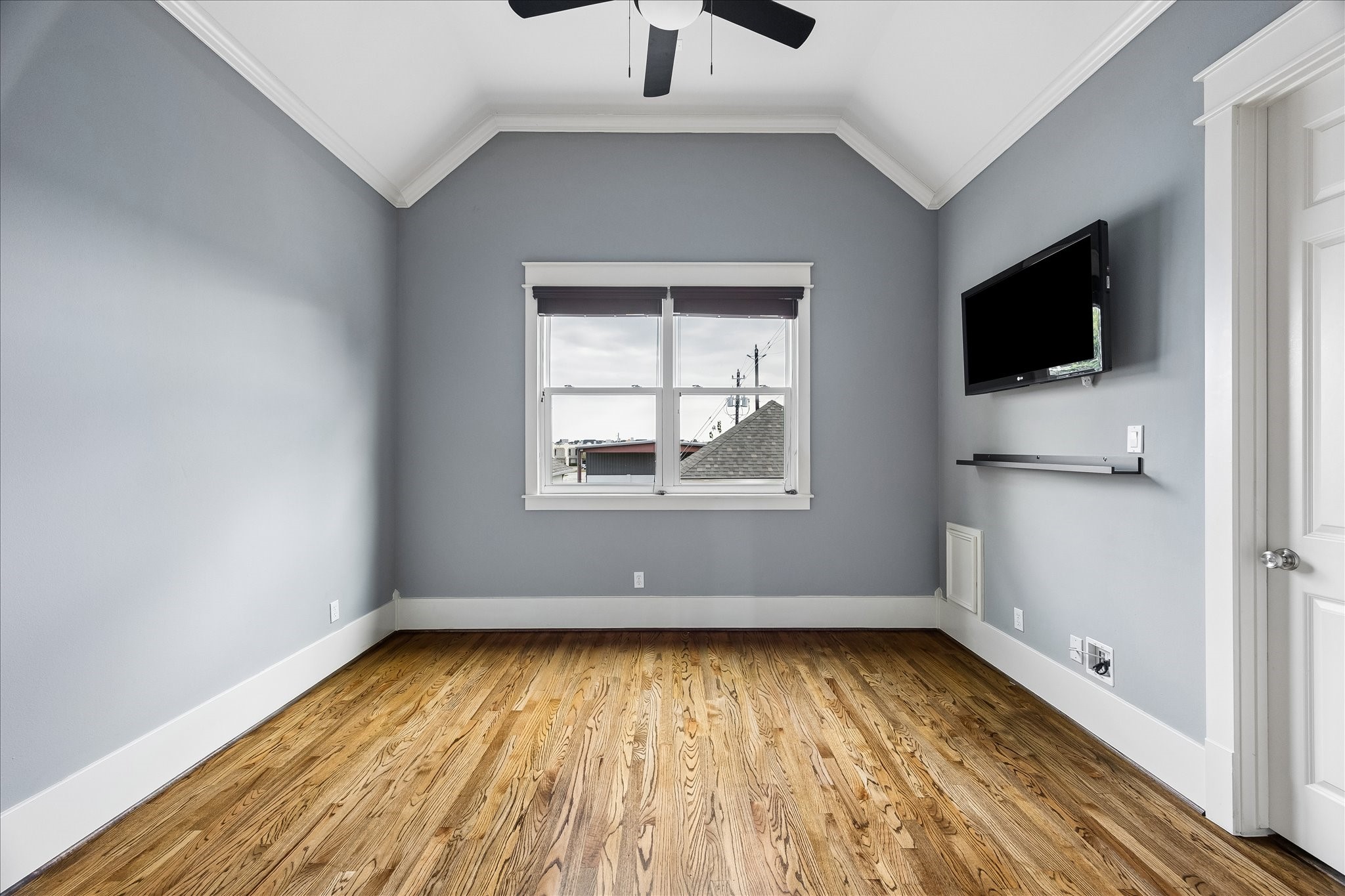 Rich hardwood floors, a vaulted ceiling, and soft natural light bring warmth and character to this inviting secondary bedroom.