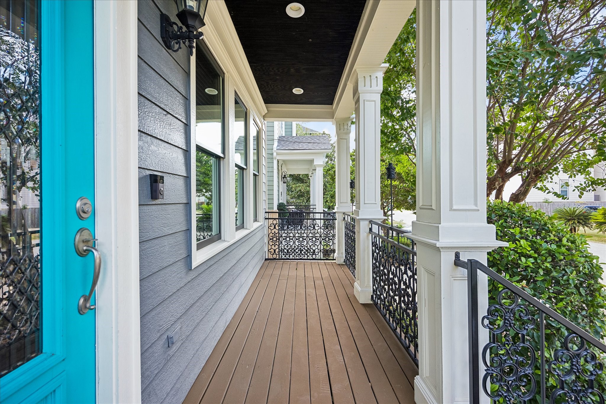A classic covered front porch with substantial columns and ornate ironwork offers a charming place to enjoy the neighborhood surroundings.