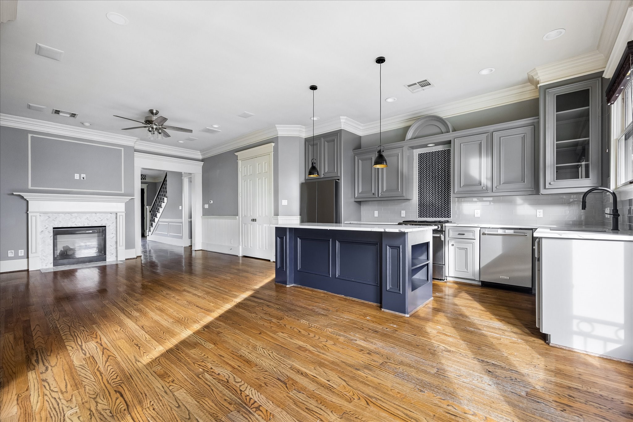 A sweeping view highlights the natural connection between the kitchen and living area, with the fireplace anchoring the far end. A sweeping view highlights the natural connection between the kitchen and living area, with the fireplace anchoring the far end.