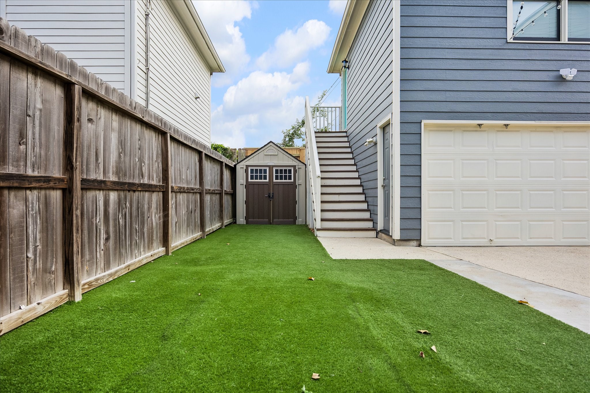 A fenced outdoor space with low-maintenance turf, a garden shed, and easy access to the garage apartment.