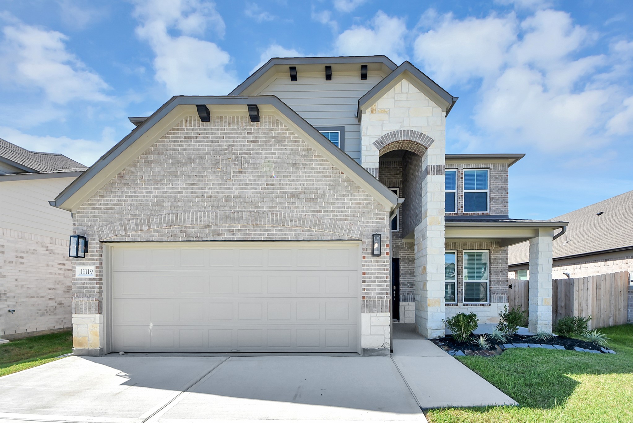 This home boasts lush green grass and meticulous landscaping. Its premium elevation showcases an exquisite blend of brick and stone features, complemented by modern coach lighting
