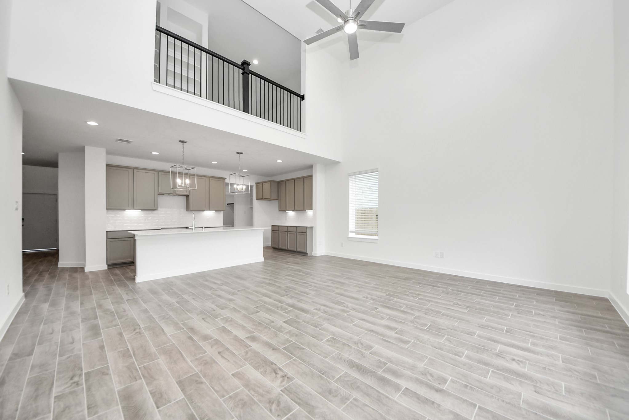 Relax and unwind in this inviting family room, illuminated by abundant natural light streaming in through tall windows, complemented by high ceilings and stunning flooring. Stay comfortable year-round with the gentle breeze from the ceiling fan, creating the perfect atmosphere for family gatherings.