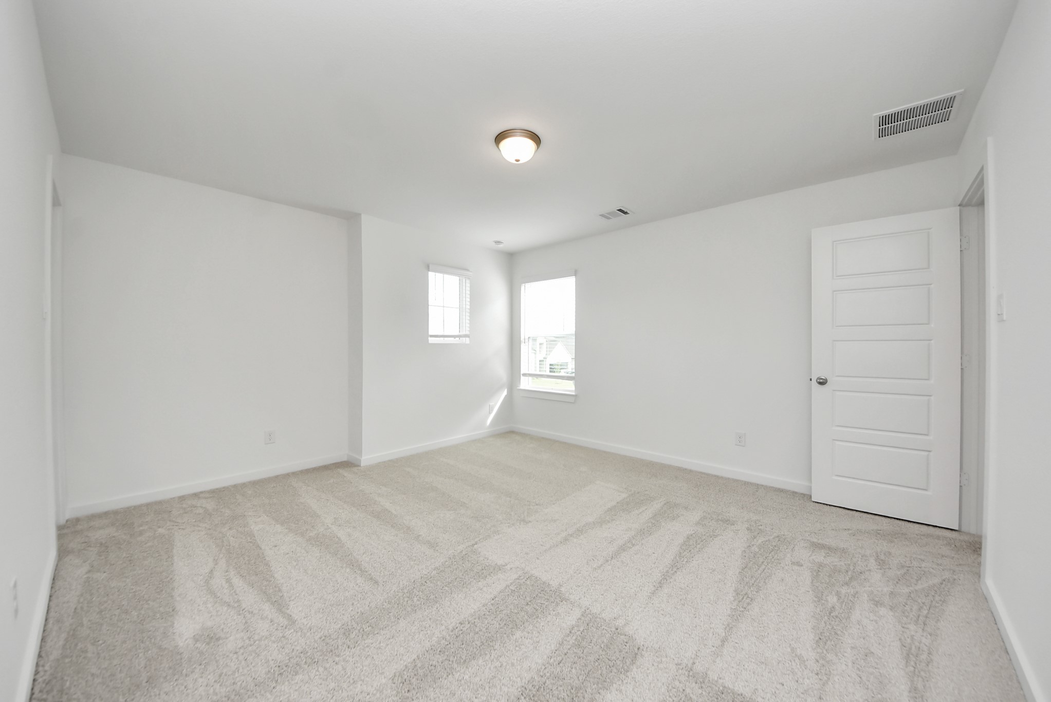 Secondary bedroom features plush carpeting, large windows that let in plenty of natural light, bright paint, and spacious closets.