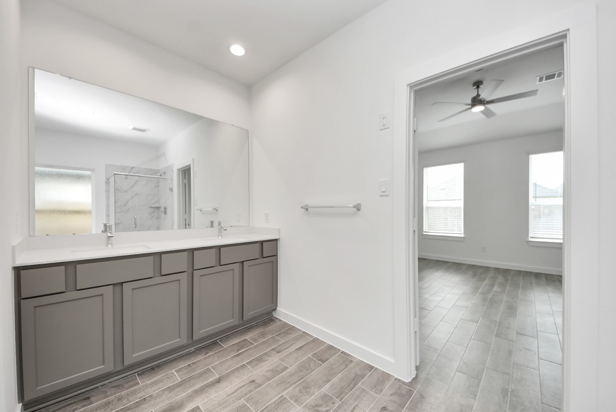 Elevate your daily routine at the elegant vanity, now equipped with double sinks, light countertops, modern hardware, and beautiful recessed lights.