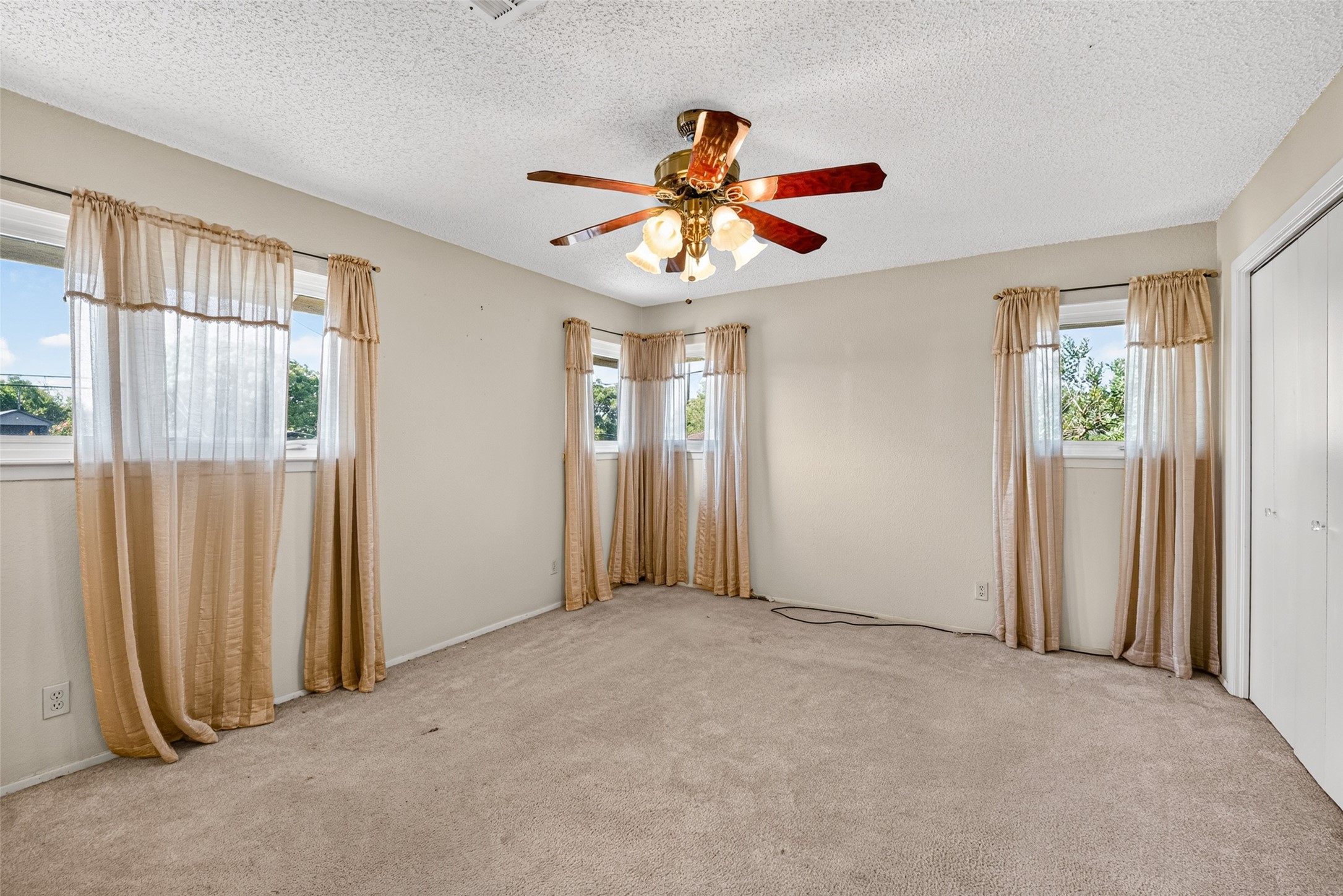 Primary bedroom facing the front of the house with multiple closets and ceiling fan