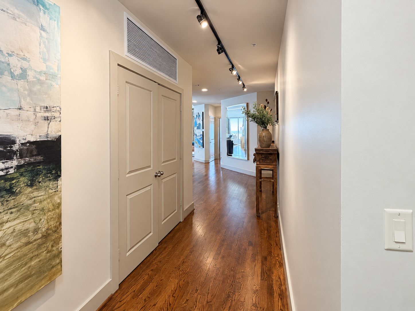 From the moment you arrive, the long gallery-style entry creates a sense of privacy and anticipation before opening into the main living spaces. Warm hardwood floors, art lighting and clean architectural lines set the tone for the refined living found throughout the residence.
