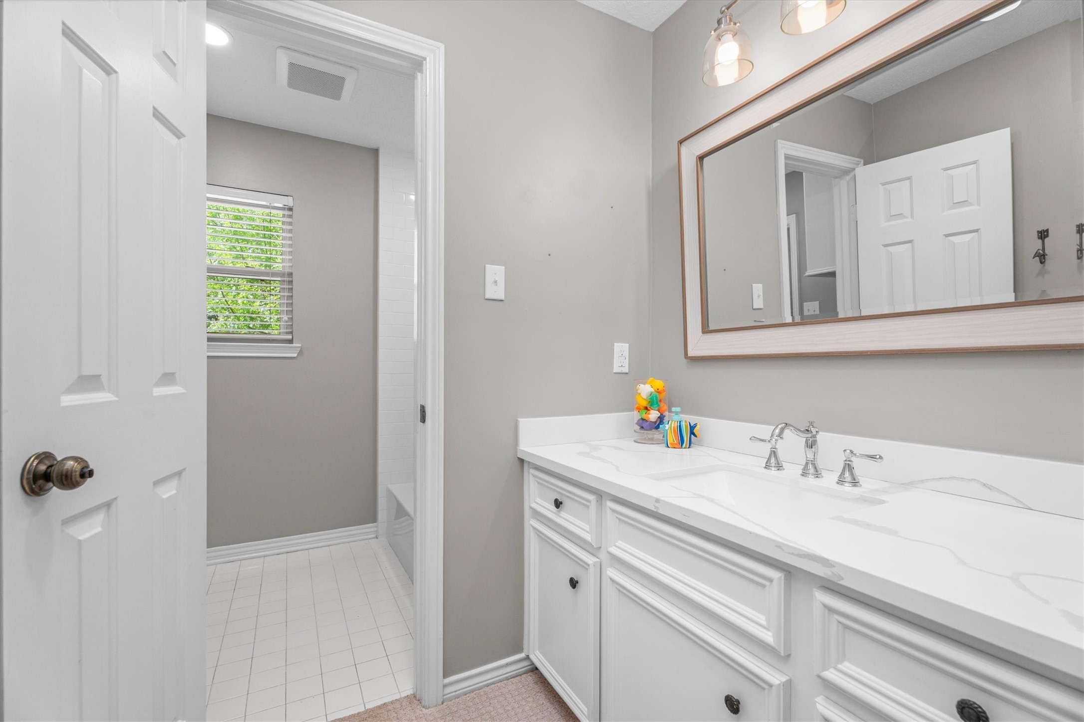 One of two secondary bathrooms is jack-and-jill style, with a private vanity area, updated with lighting, countertops, sink and fixtures in 2021.