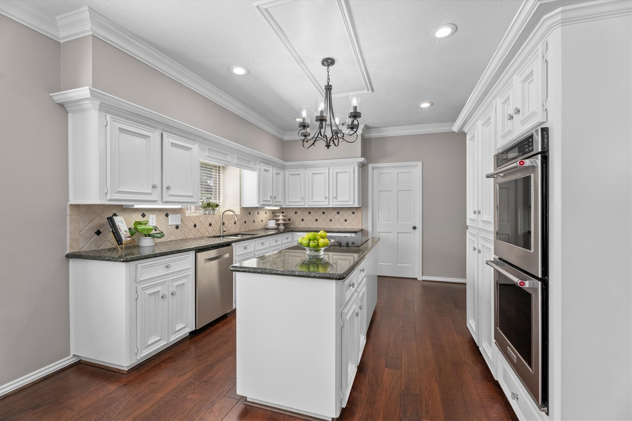 The kitchen is anchored by an oversized island with cooktop, opposite double ovens.