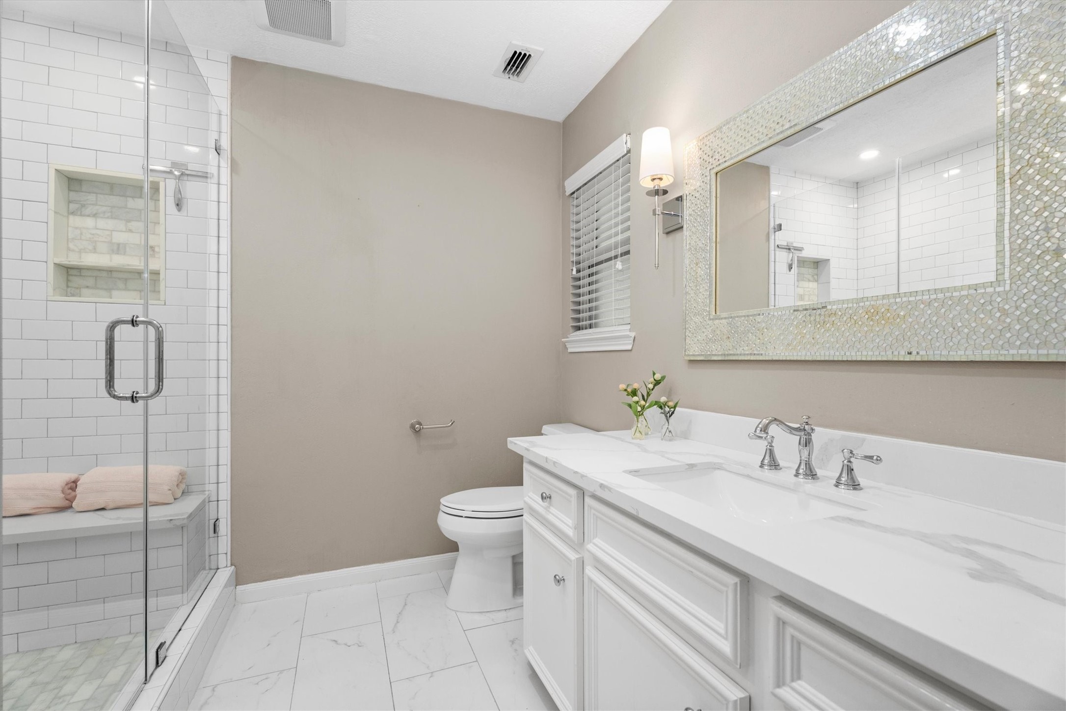 This bathroom is a dream! Updated vanity, lighting, tile, fixtures, and a large, glass-enclosed shower with bench.