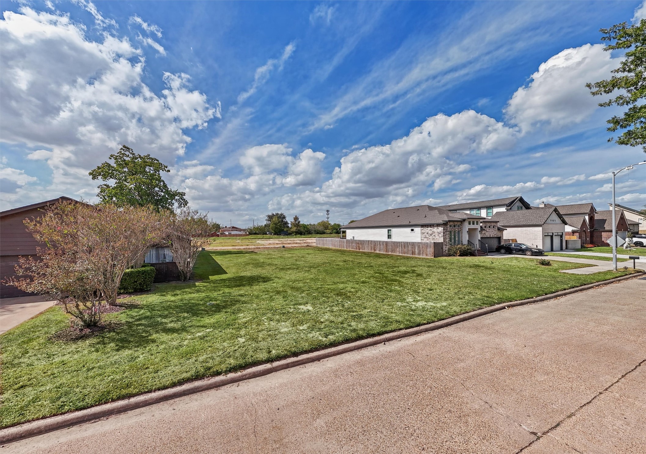 YOUR DREAM HOME STARTS HERE! Imagine the possibilities with this spacious, cleared residential lot nestled among beautiful established homes! This street-level view showcases the property's generous open space, attractive neighborhood setting, and mature trees nearby.