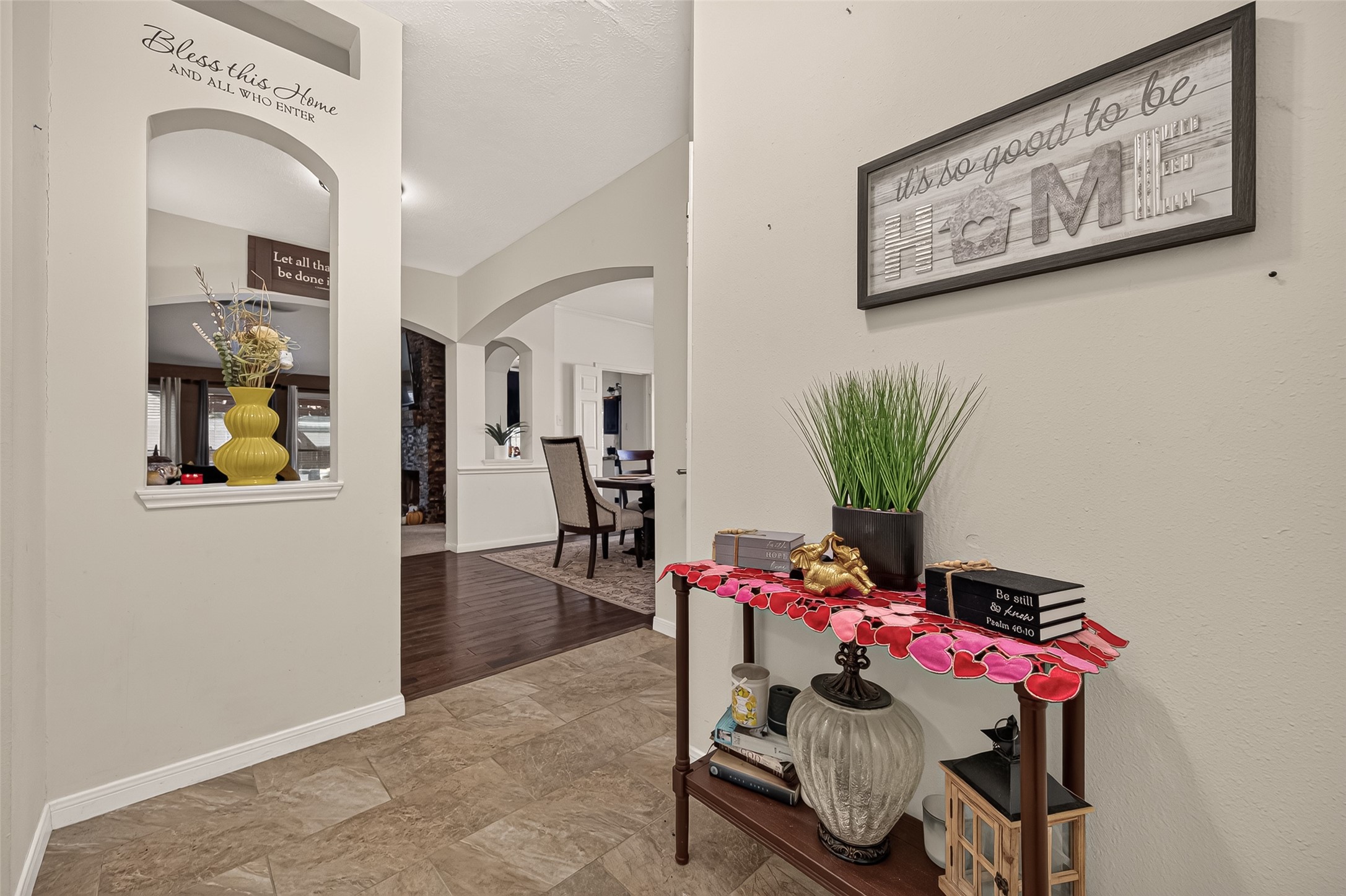 Charming entryway with stylish decor and inviting archways leads into a spacious dining area, featuring elegant flooring and warm, welcoming accents.