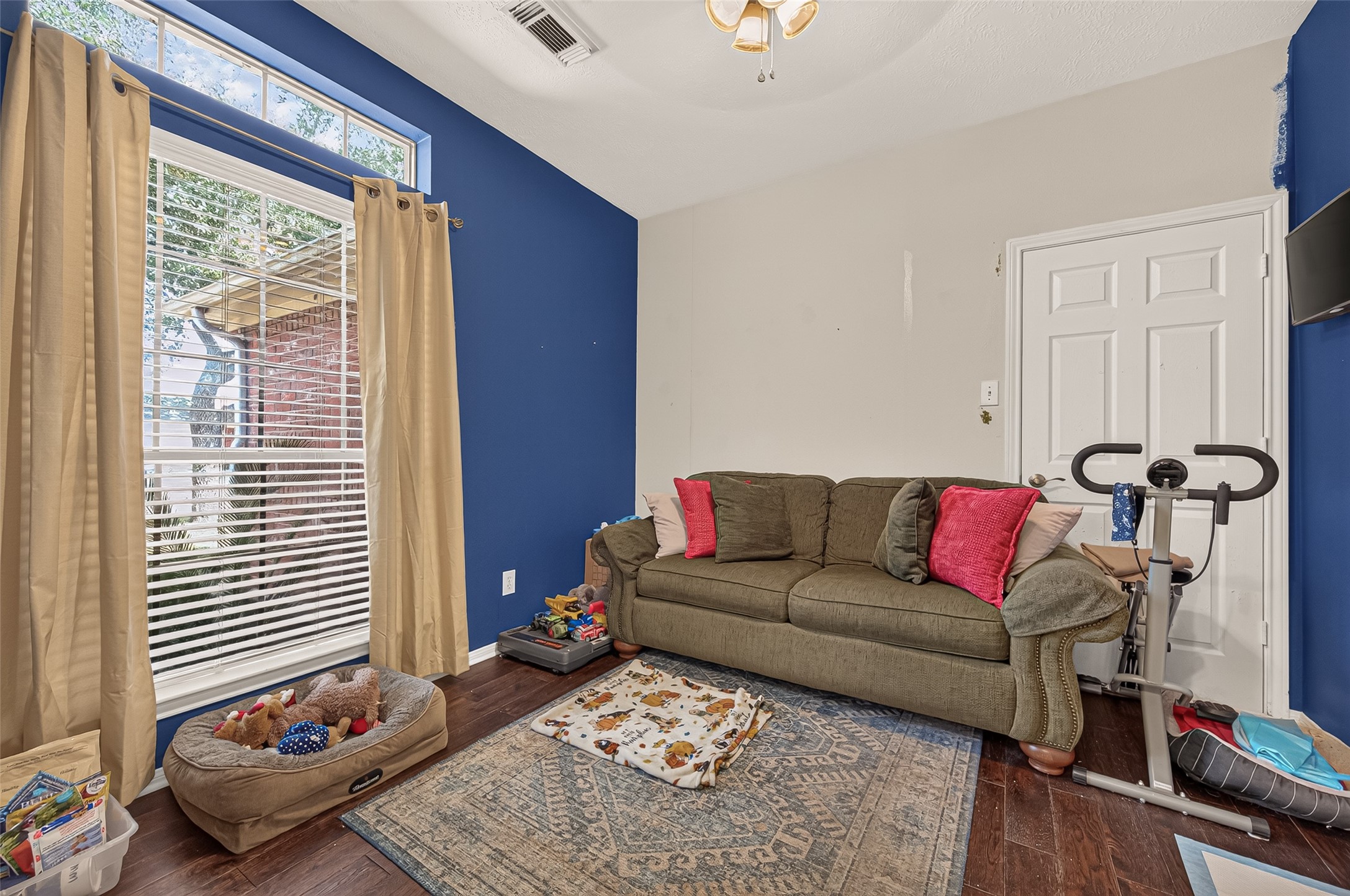 Discover a versatile space perfect for a home office, cozy bedroom, or creative flex room, highlighted by natural light and vibrant blue accents.