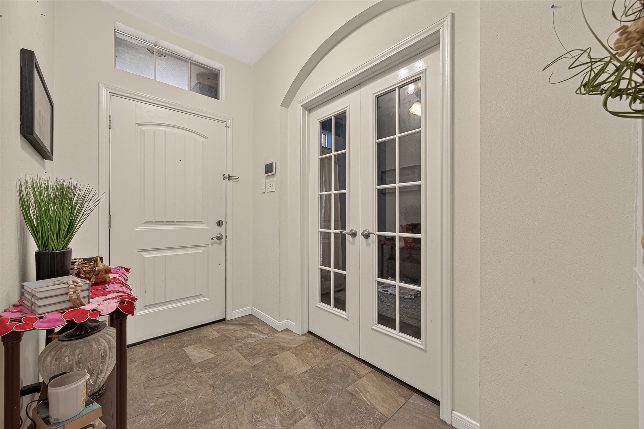 Elegant entryway featuring double French doors, abundant natural light, and stylish tile flooring, creating a welcoming first impression.