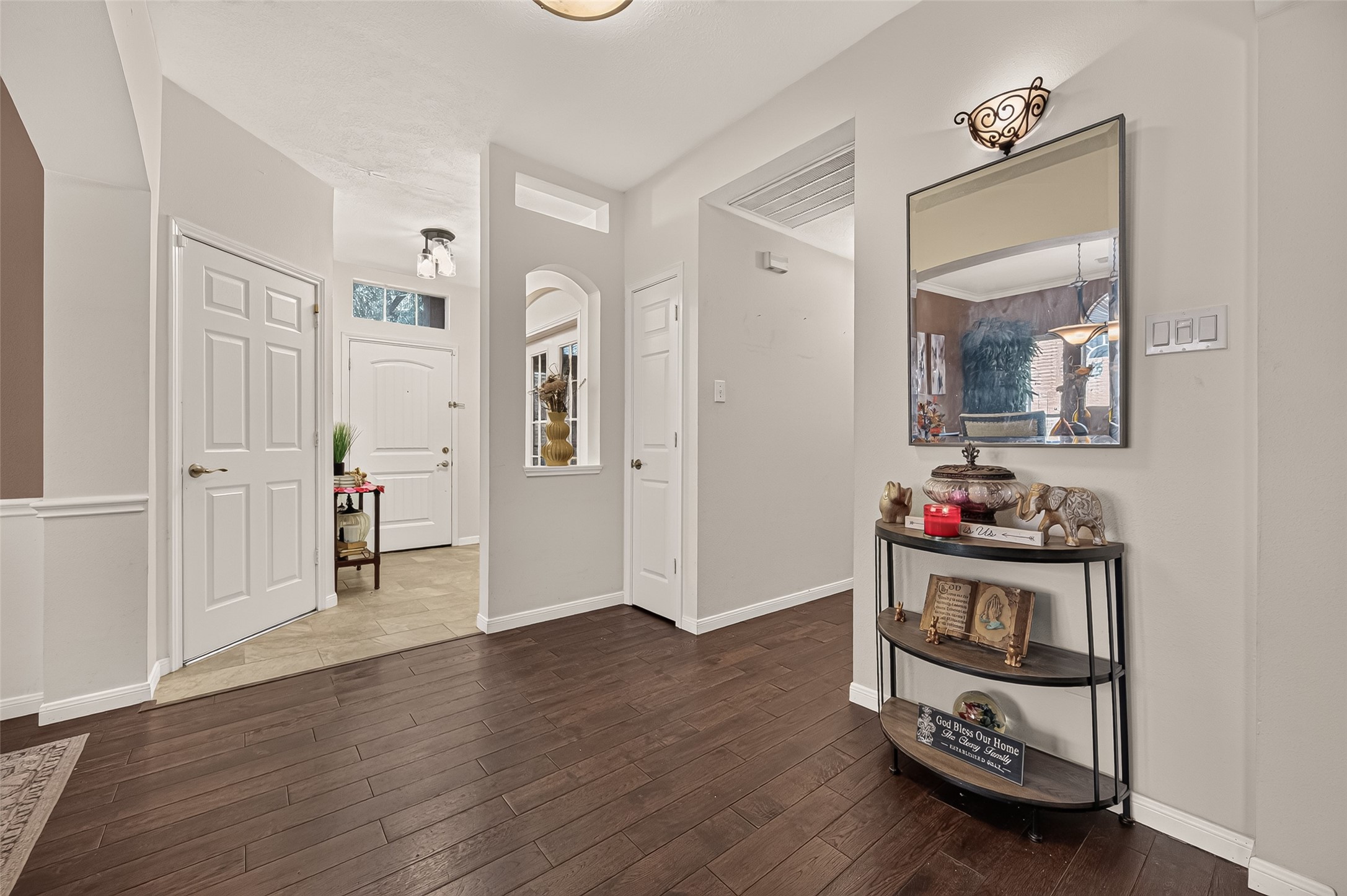 Inviting entryway with elegant dark egineered laminate flooring, fresh neutral walls, and stylish lighting, creating a warm and welcoming atmosphere.
