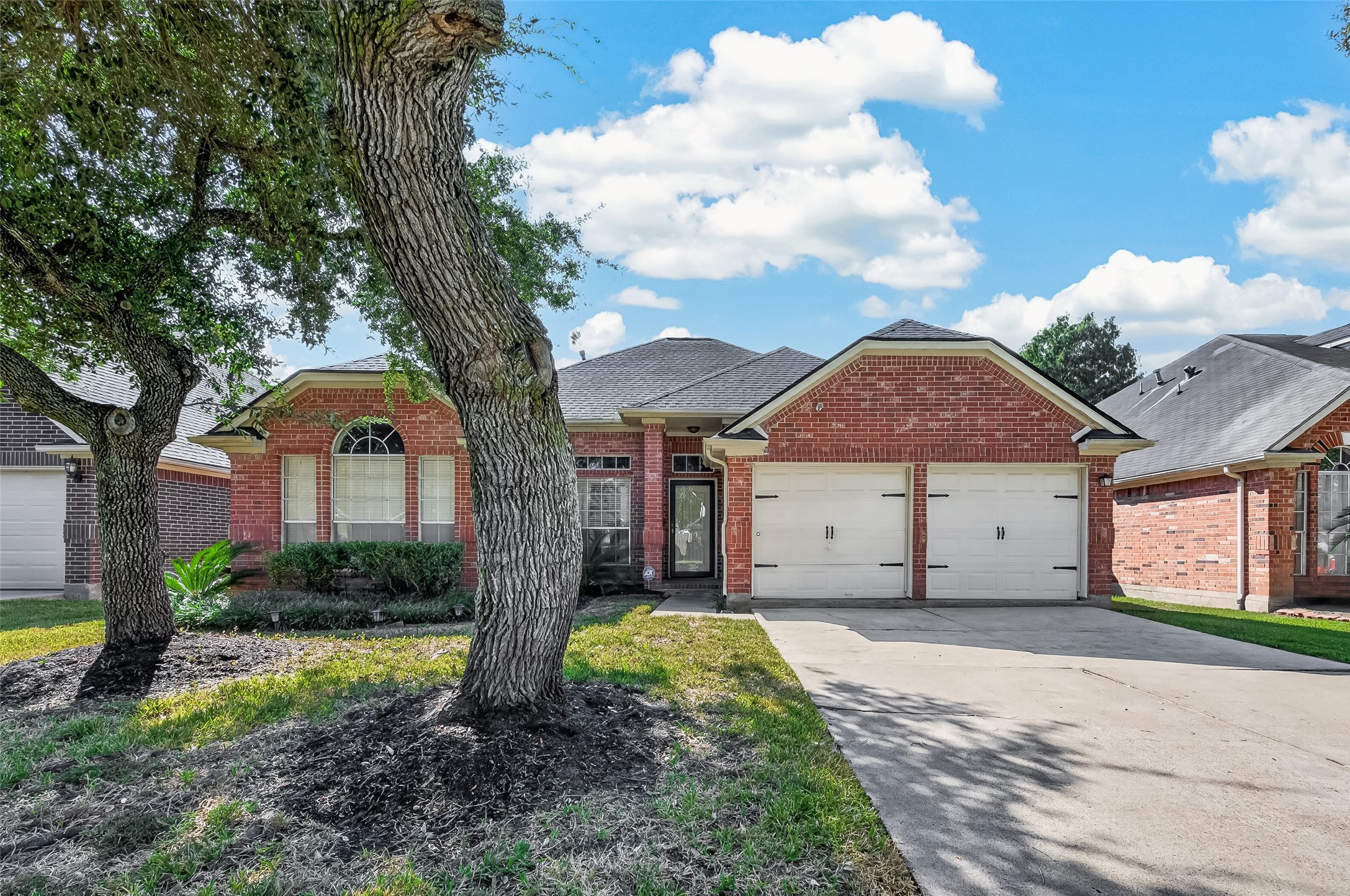 Charming brick home with a spacious two-car garage, nestled among mature trees and featuring a welcoming arched window and well-maintained landscaping. Charming brick home with a spacious two-car garage, nestled among mature trees and featuring a welcoming arched window and well-maintained landscaping.