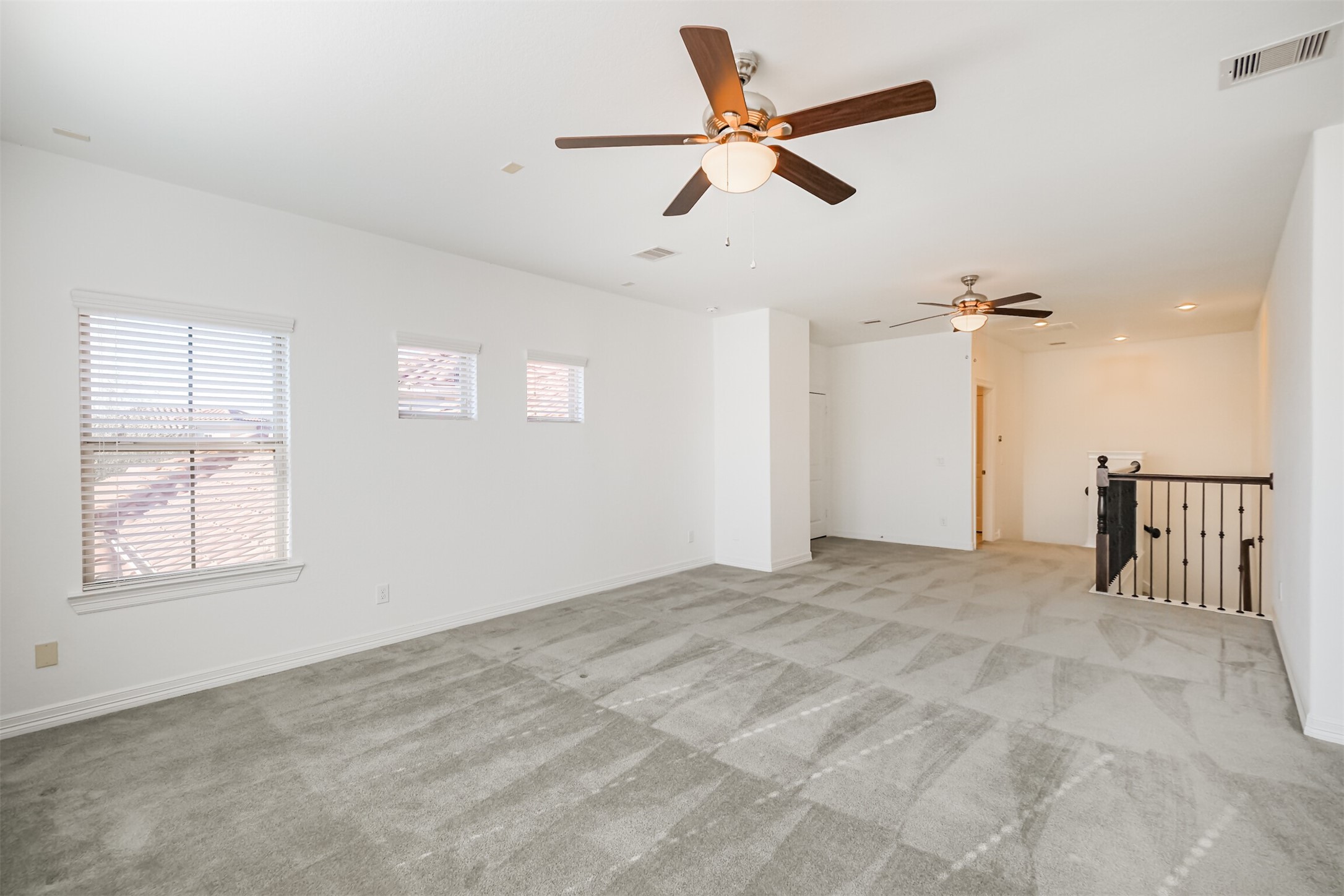 Expansive game room on the second floor offers comfortable space with two ceiling fans and half bath.