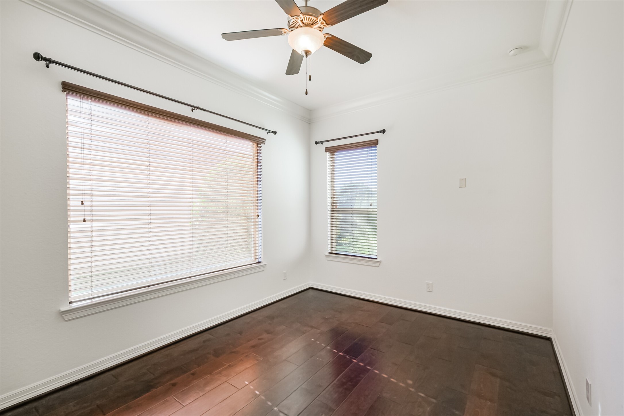 Another view of this bright, versatile space, which would be ideal as a guest bedroom, workout space, craft room or study, features two large windows and ceiling fan.