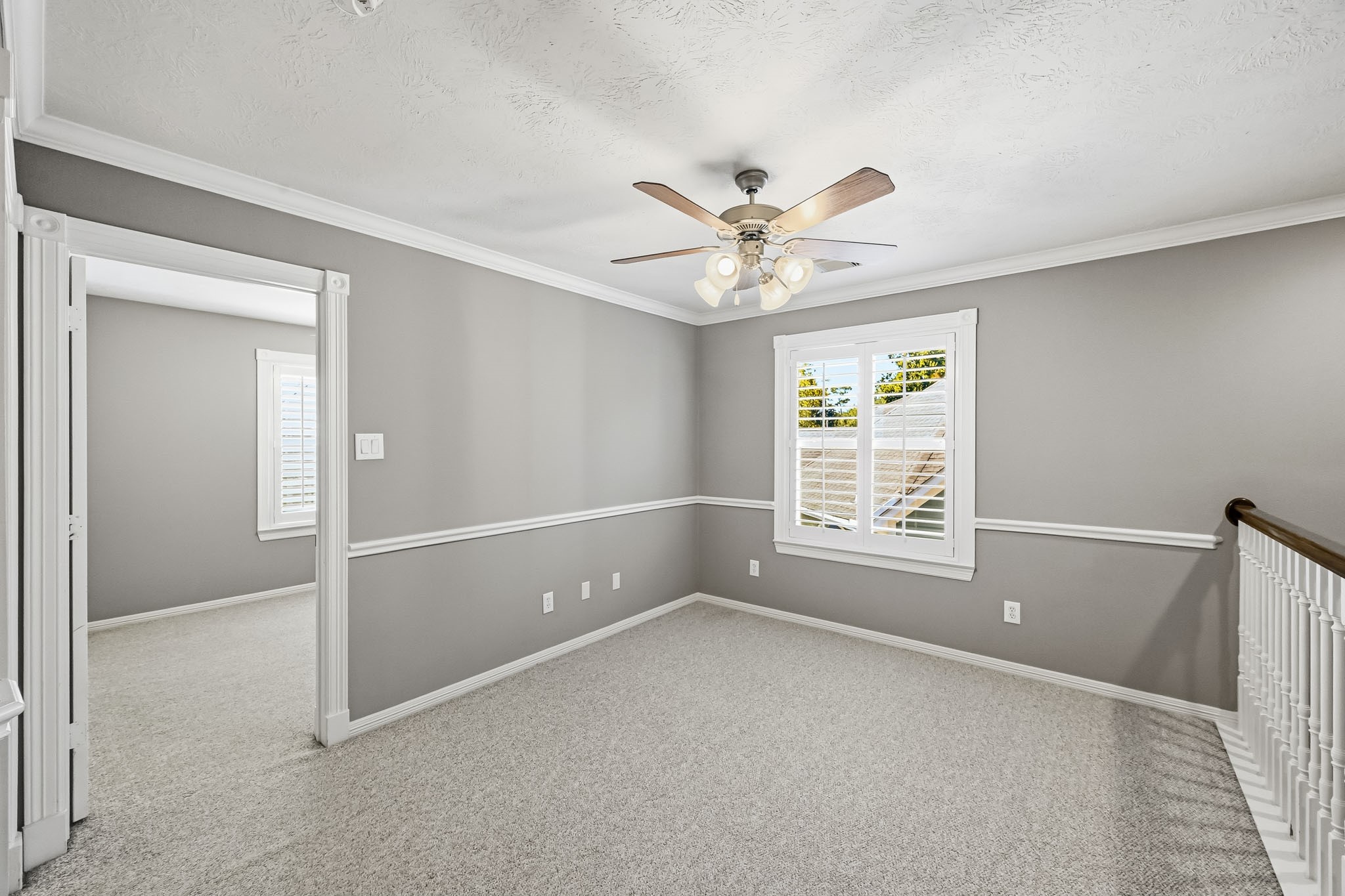 Versatile upstairs landing with Berber carpet, ceiling fan, and plantation shutters. Ideal for a sitting area, study space, playroom, or additional living area.