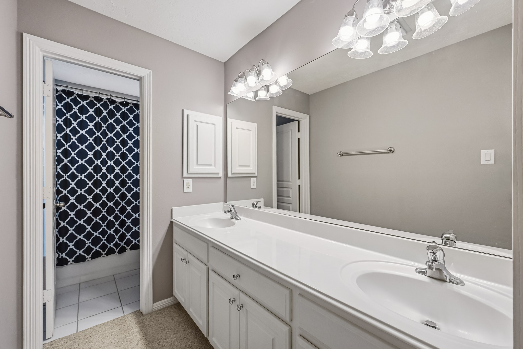 Spacious secondary bathroom with dual sinks, generous vanity storage, and a separate tub/shower area.