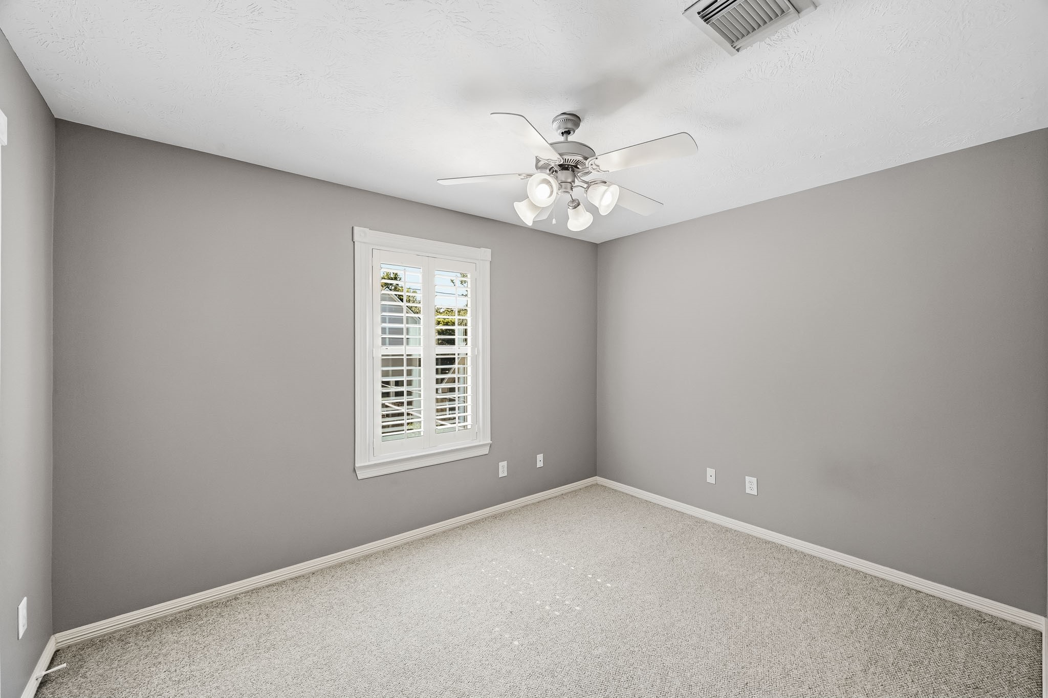 Comfortable secondary bedroom featuring Berber carpet, neutral paint, ceiling fan, and plantation shutters.