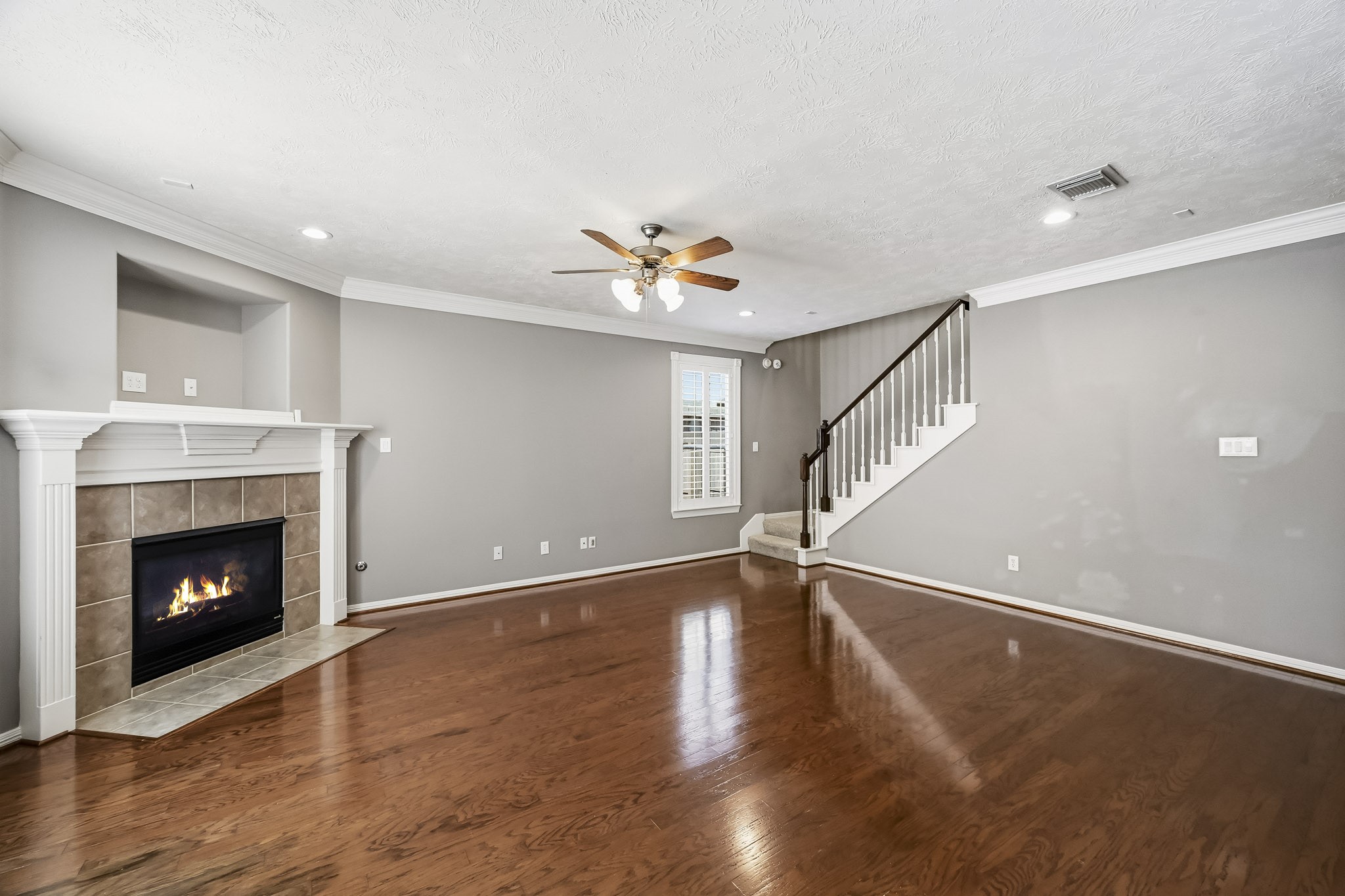 Spacious family room with beautiful hardwood floors, a gas fireplace, crown molding, and plantation shutters. Spacious family room with beautiful hardwood floors, a gas fireplace, crown molding, and plantation shutters.