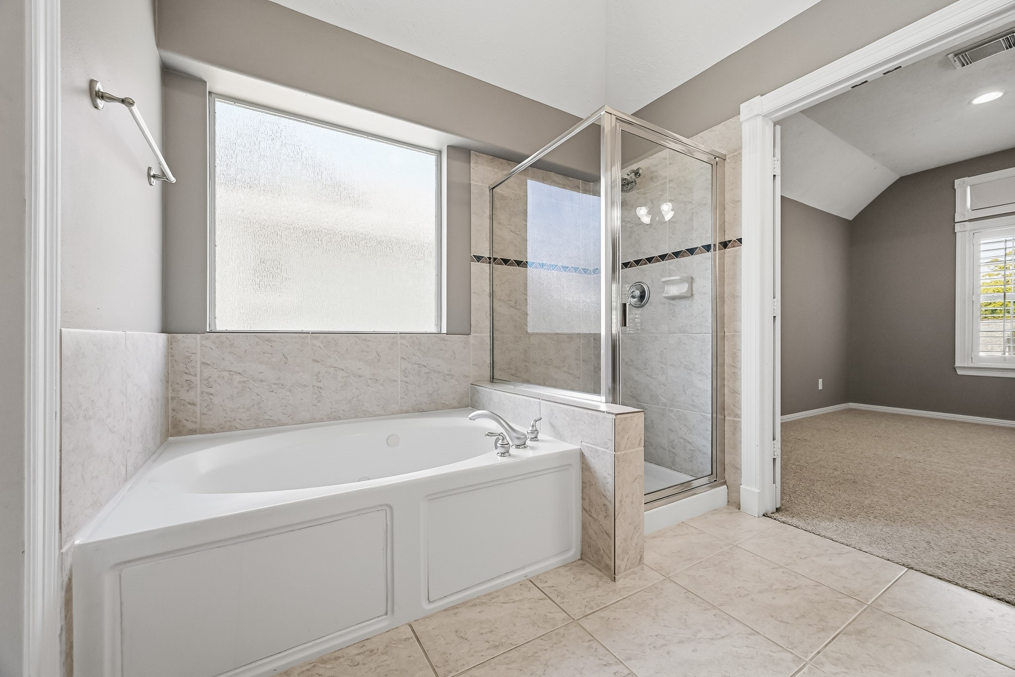 Relax in the primary bathroom's jetted soaking tub, complemented by a separate glass-enclosed shower and natural light.