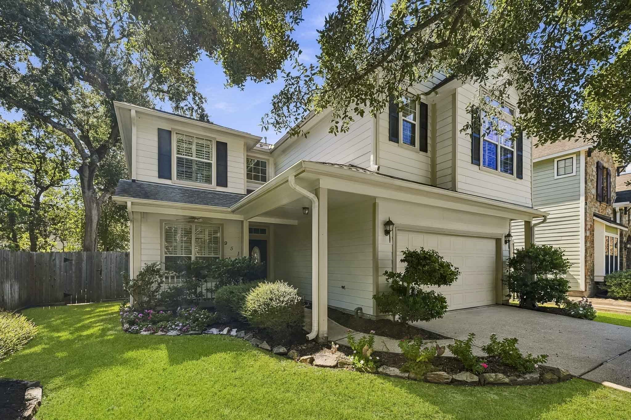 Welcoming covered front porch, mature landscaping, and an attached two-car garage with an extended driveway.