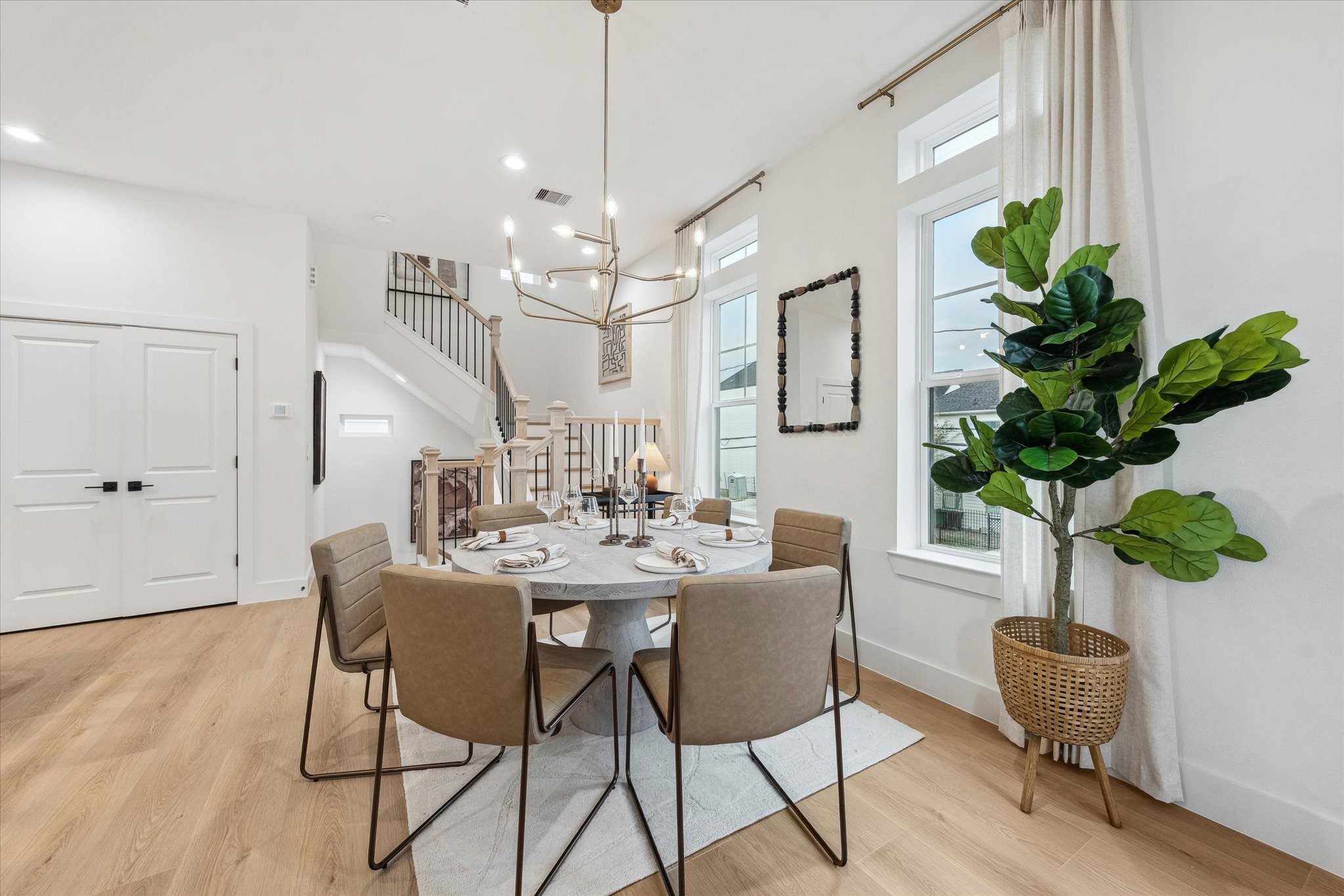 Elegant dining area with a modern chandelier, ample natural light, and stylish seating, perfect for entertaining.