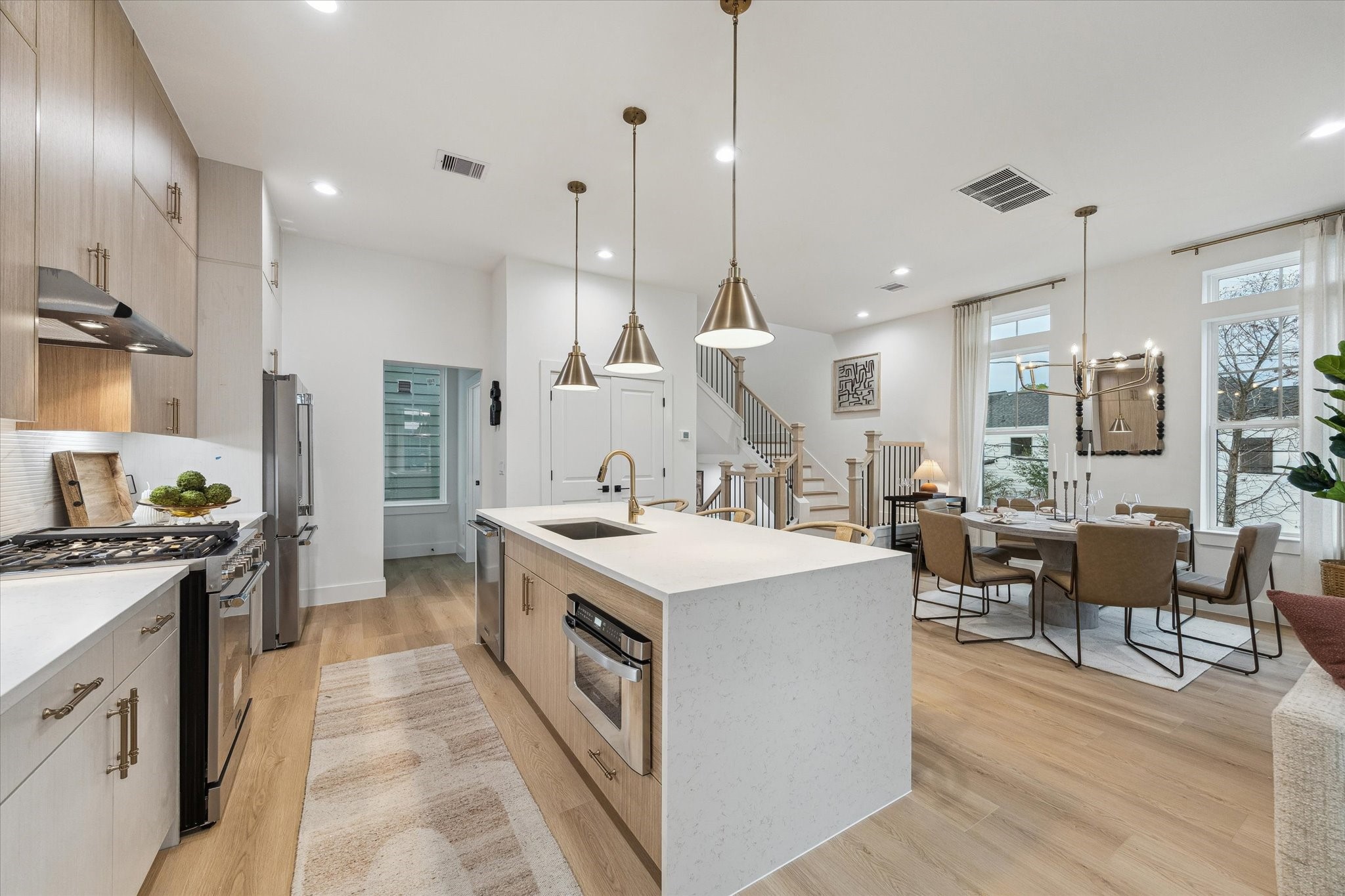 Discover a bright open-concept kitchen and dining area featuring sleek cabinetry, modern light fixtures, and a spacious island, perfect for entertaining.