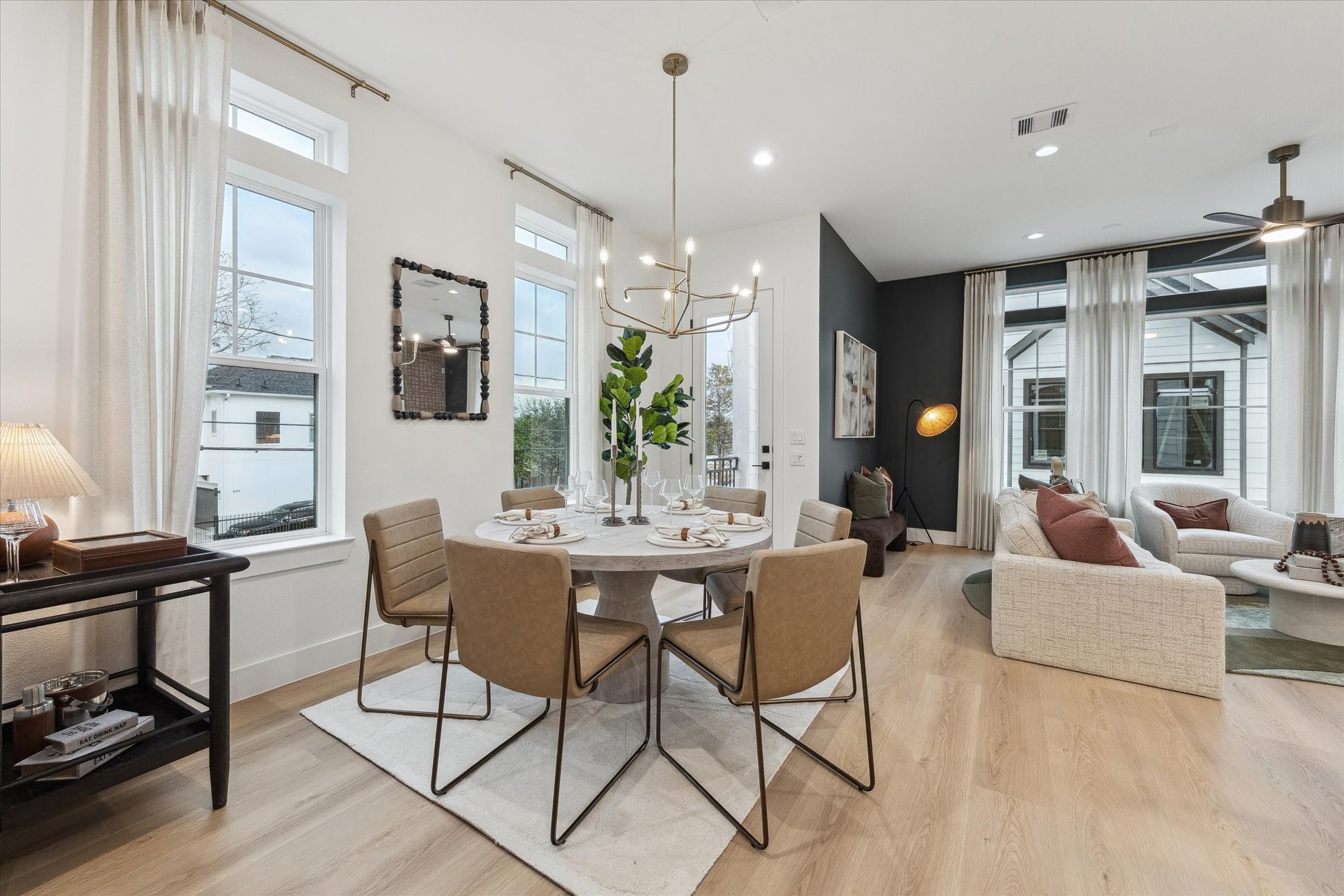 Elegant open-concept living and dining area featuring a modern chandelier, large windows for natural light, and stylish furnishings for a warm, inviting atmosphere.