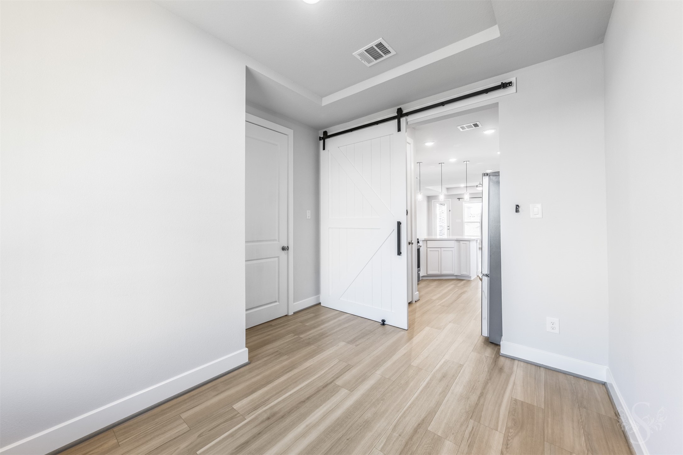 Beautiful wood flooring and a tray ceiling create a stylish setting for memorable meals in the formal dining room. A sliding barn door adds character while allowing the room to be closed off from the kitchen for more intimate gatherings.