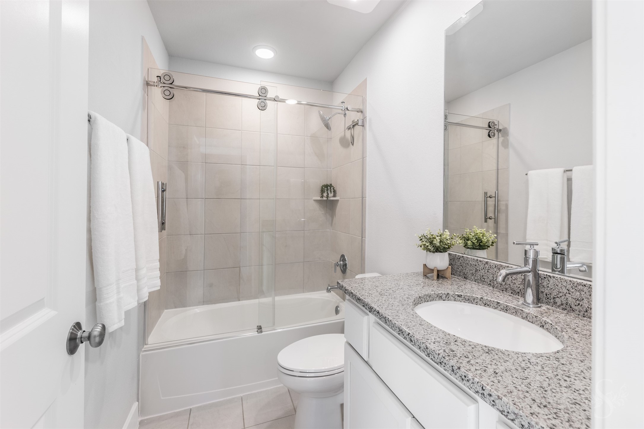The upstairs bath features a beautiful granite vanity with white cabinetry and a polished chrome faucet. A tiled tub and shower combination with sliding glass doors offers everyday convenience for the family.