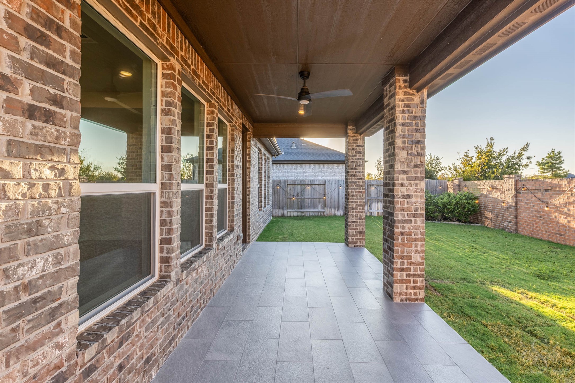 The spacious covered patio features beautiful tile flooring and a ceiling fan, creating an inviting setting for morning coffee or relaxed evenings with friends. Enjoy views of the fenced back yard with plenty of green space for children and pets to play.