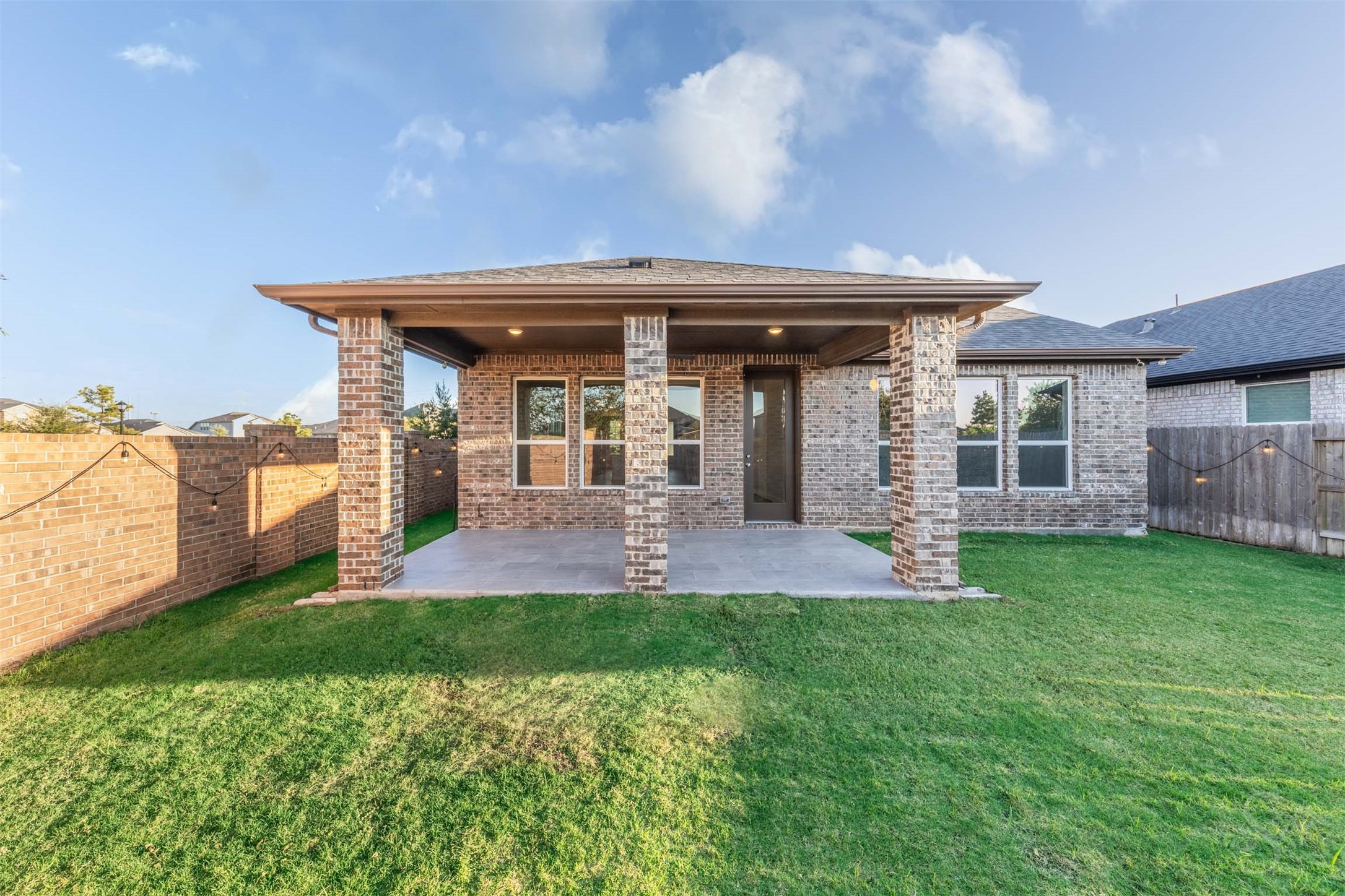The spacious back yard offers plenty of green space for playing, gardening or enjoying the sunshine. A covered patio framed by brick columns provides an inviting spot to relax or entertain friends.