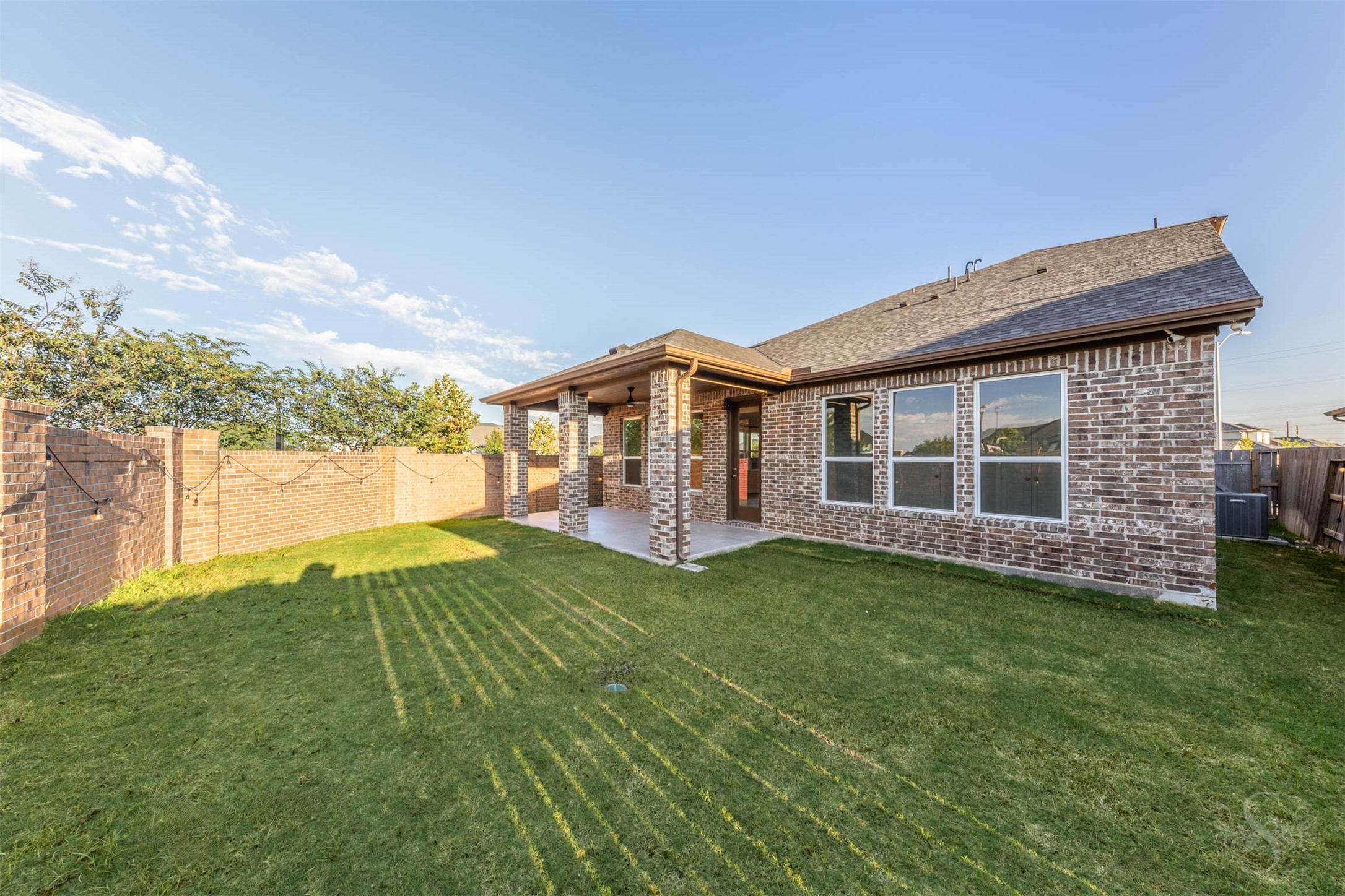 The spacious back yard offers plenty of green space for playing, gardening or enjoying the sunshine. A covered patio framed by brick columns provides an inviting spot to relax or entertain friends.