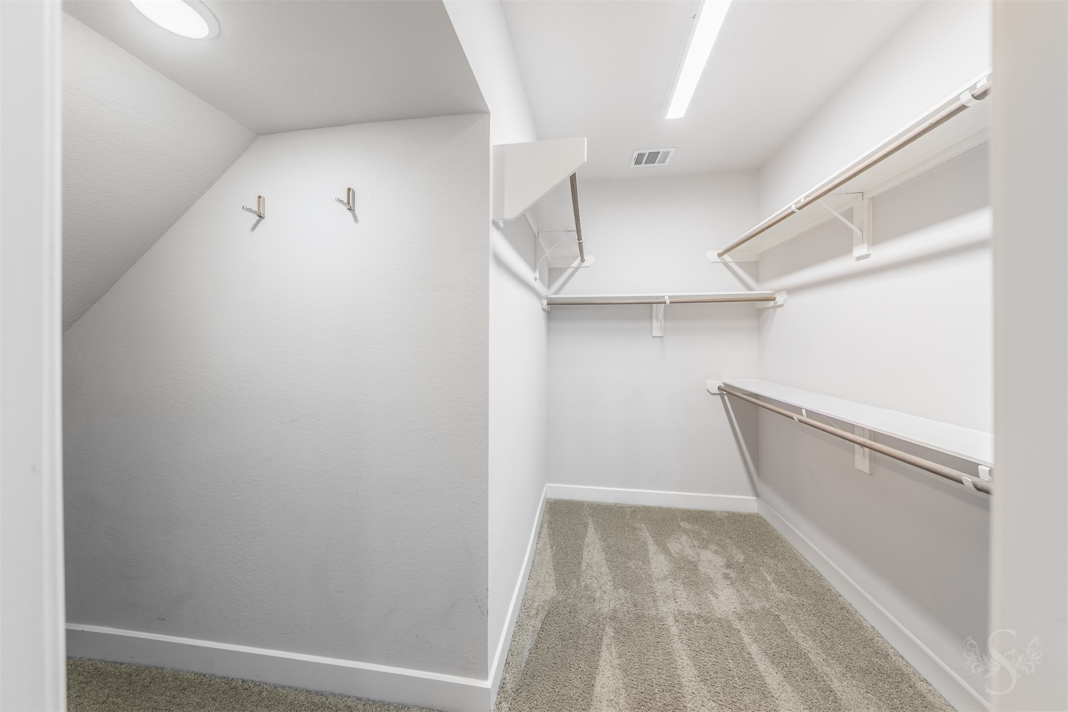 The spacious primary closet offers multiple hanging rods and overhead shelving to keep your wardrobe organized. An additional nook provides space for shoes, luggage or seasonal storage.