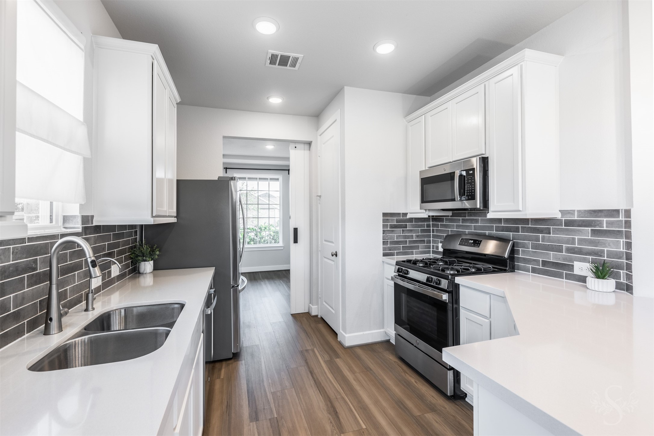A stainless steel gas range and built-in microwave complement the kitchens beautiful white cabinetry and quartz counters. Generous counter space, a double-basin sink and abundant cabinet storage make meal preparation a pleasure.