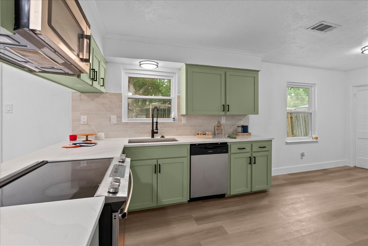 A bright and inviting kitchen featuring sleek green cabinets, modern appliances, and ample counter space for culinary creativity.