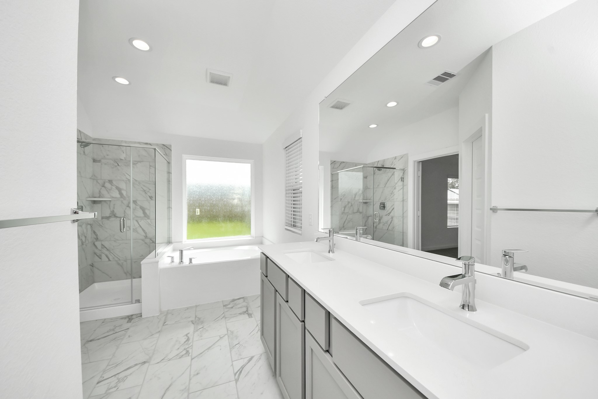 Escape to a spa-like oasis in this primary bathroom. Enjoy a walk-in shower with tile surround, a separate garden tub with custom detailing, and an elegant vanity featuring light countertops, modern hardware, and beautiful vanity lights. Experience luxury and relaxation in every detail. Sample photo of completed home with similar floor plan. Actual colors and selections may vary.