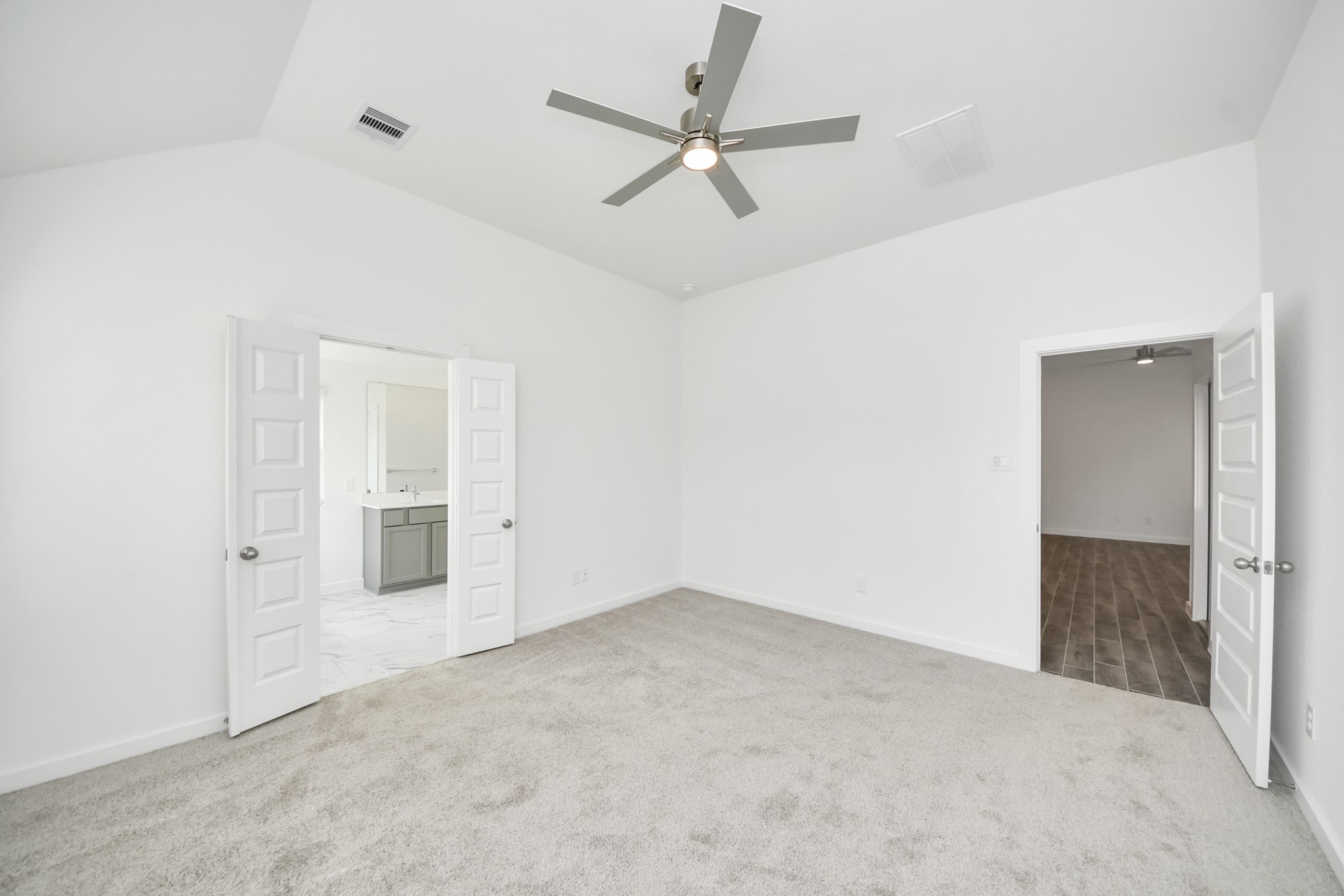 Escape and relax in the exquisite primary suite, a haven to unwind after a long day. The spacious room, located on first floor, boasts plush carpeting, soothing paint tones, high ceilings, and expansive windows adorned with privacy blinds. Sample photo of completed home with similar floor plan. Actual colors and selections may vary.