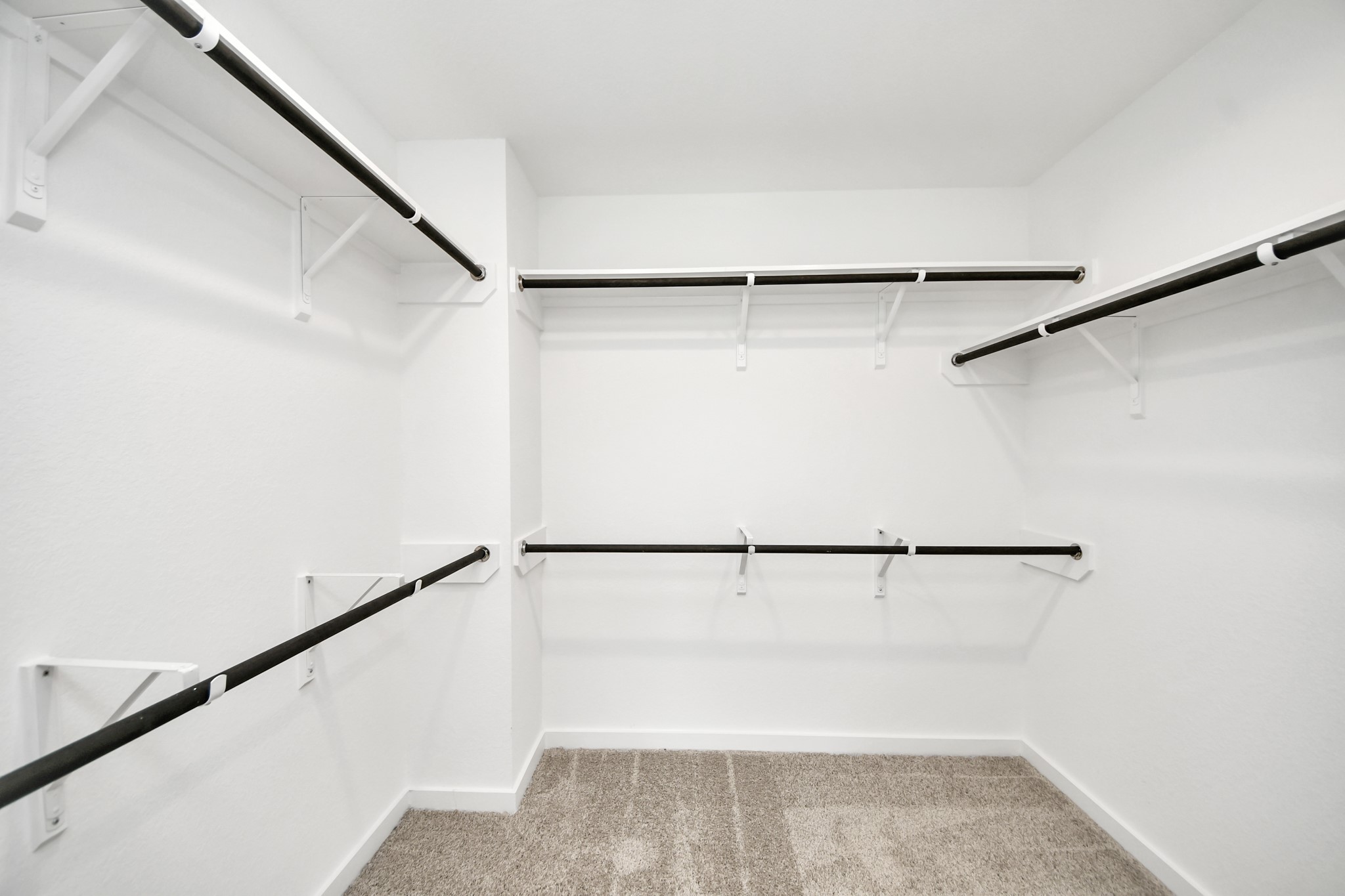 Walk-in closet that epitomizes luxury and practicality. This generously sized space features built-in shelving, offering abundant room for impeccable organization. High ceilings and recessed lighting create a bright and welcoming ambiance. Sample photo of completed home with similar floor plan. Actual colors and selections may vary.