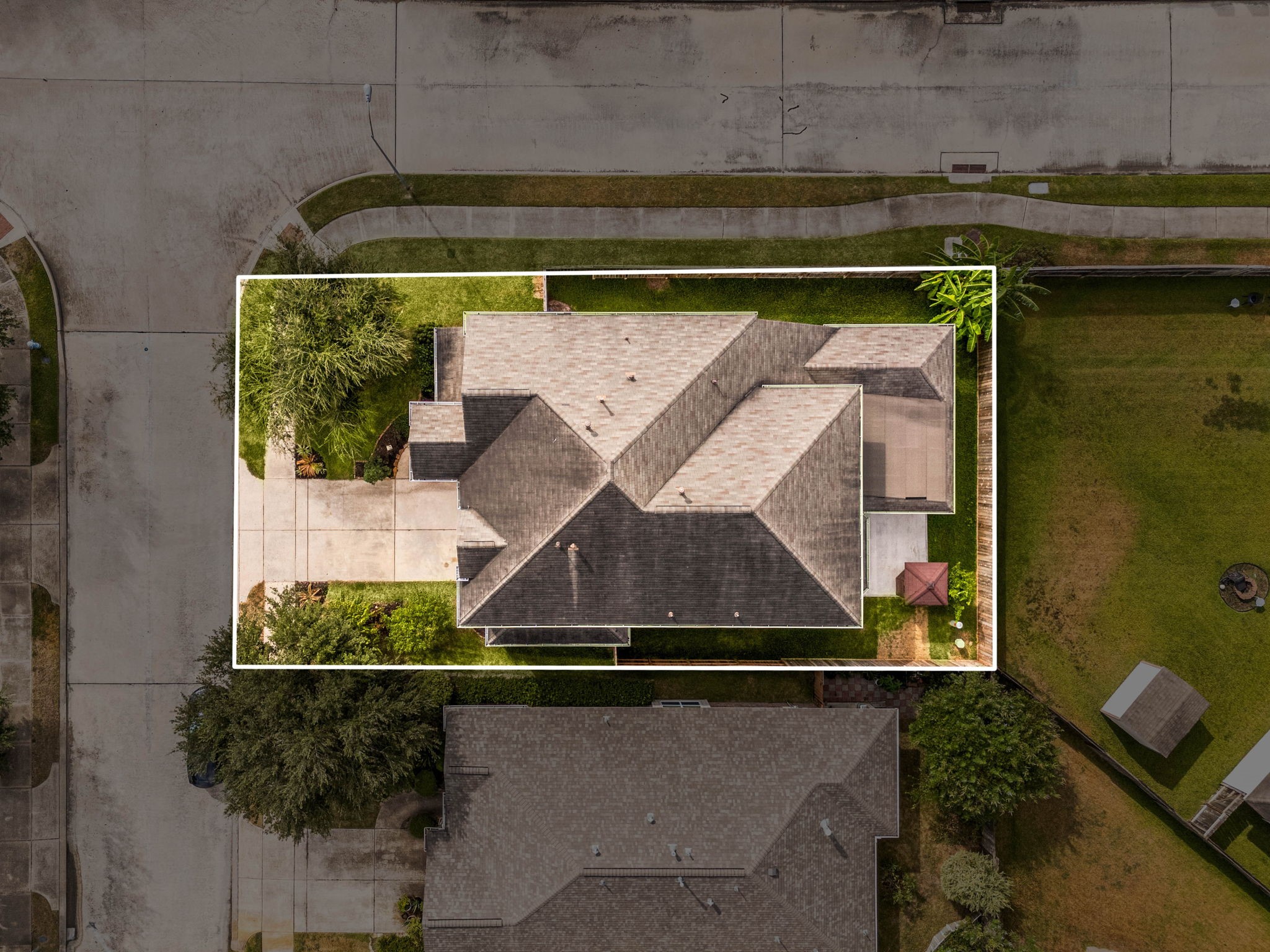 This home sits on a beautifully situated corner-lot in Katy Creek Ranch, offering extra outdoor space and enhanced privacy with only one immediate neighbor. This aerial view highlights the home's sprawling layout, expansive roofline, and highly desirable corner position within the community, providing a spacious side yard and an inviting curb appeal.