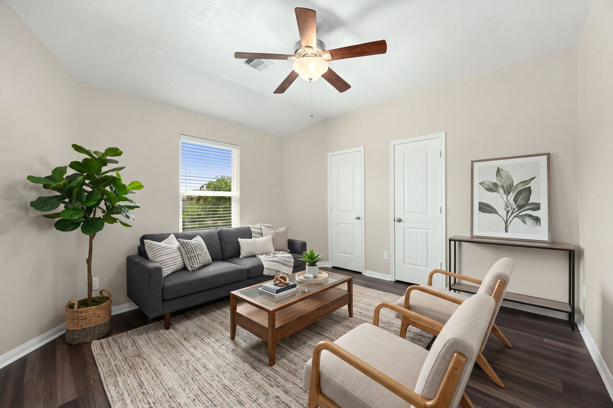This highly versatile fourth secondary bedroom is currently styled as a cozy additional sitting room, showcasing the incredible flexibility of the home's layout. The bright space features rich dark flooring, a central wood-blade ceiling fan, a large window letting in soft natural light, and dual closets that make it equally perfect as a spacious guest suite, home office, or media room. *Virtually Staged