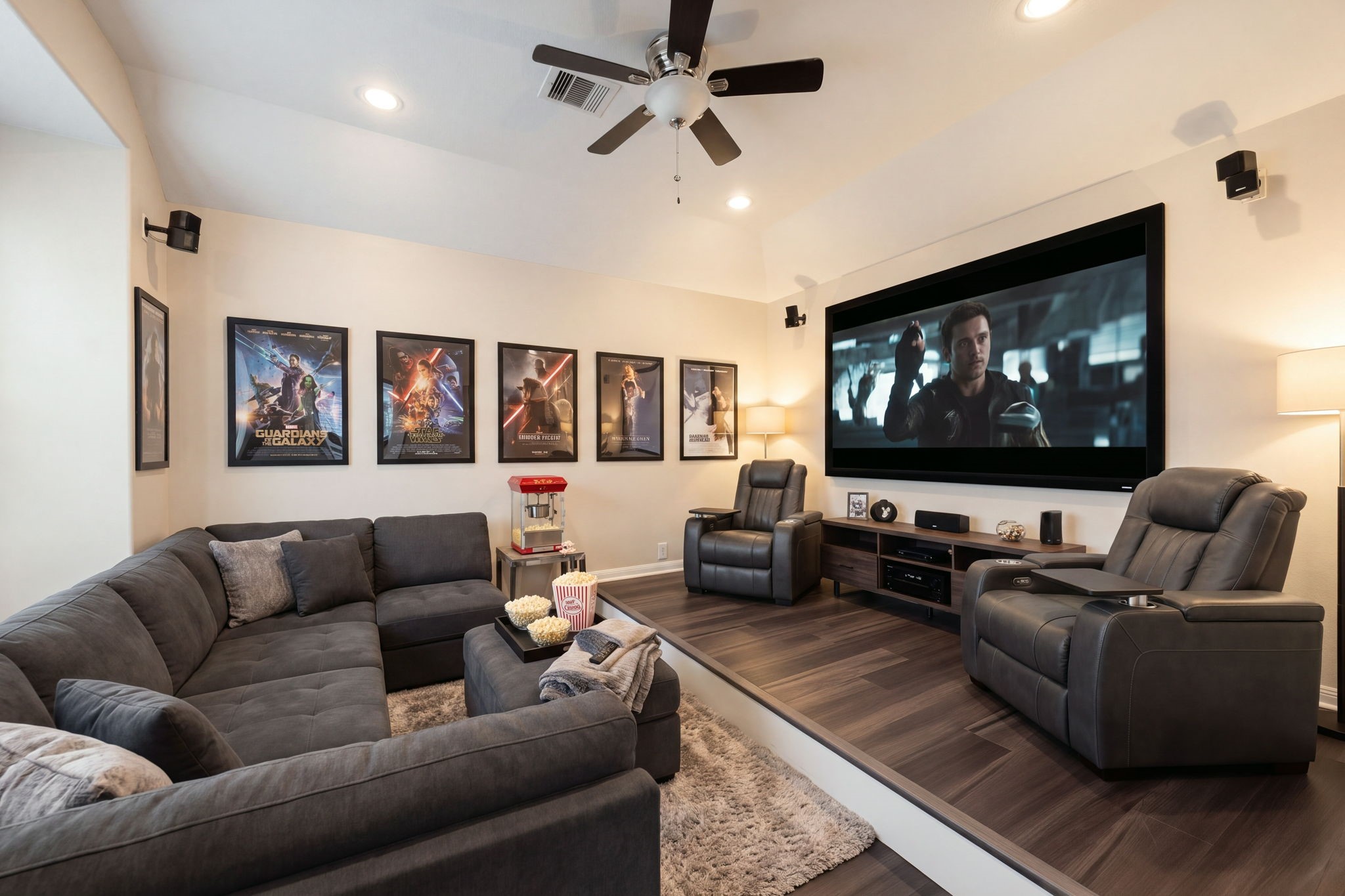 An incredible tiered media room provides the ultimate cinematic experience right at home, complete with custom multi-level riser seating. The thoughtfully designed space features rich dark wood flooring, recessed lighting, a modern ceiling fan, and wall-mounted surround sound speakers for an immersive movie-theater atmosphere. *Virtually Staged