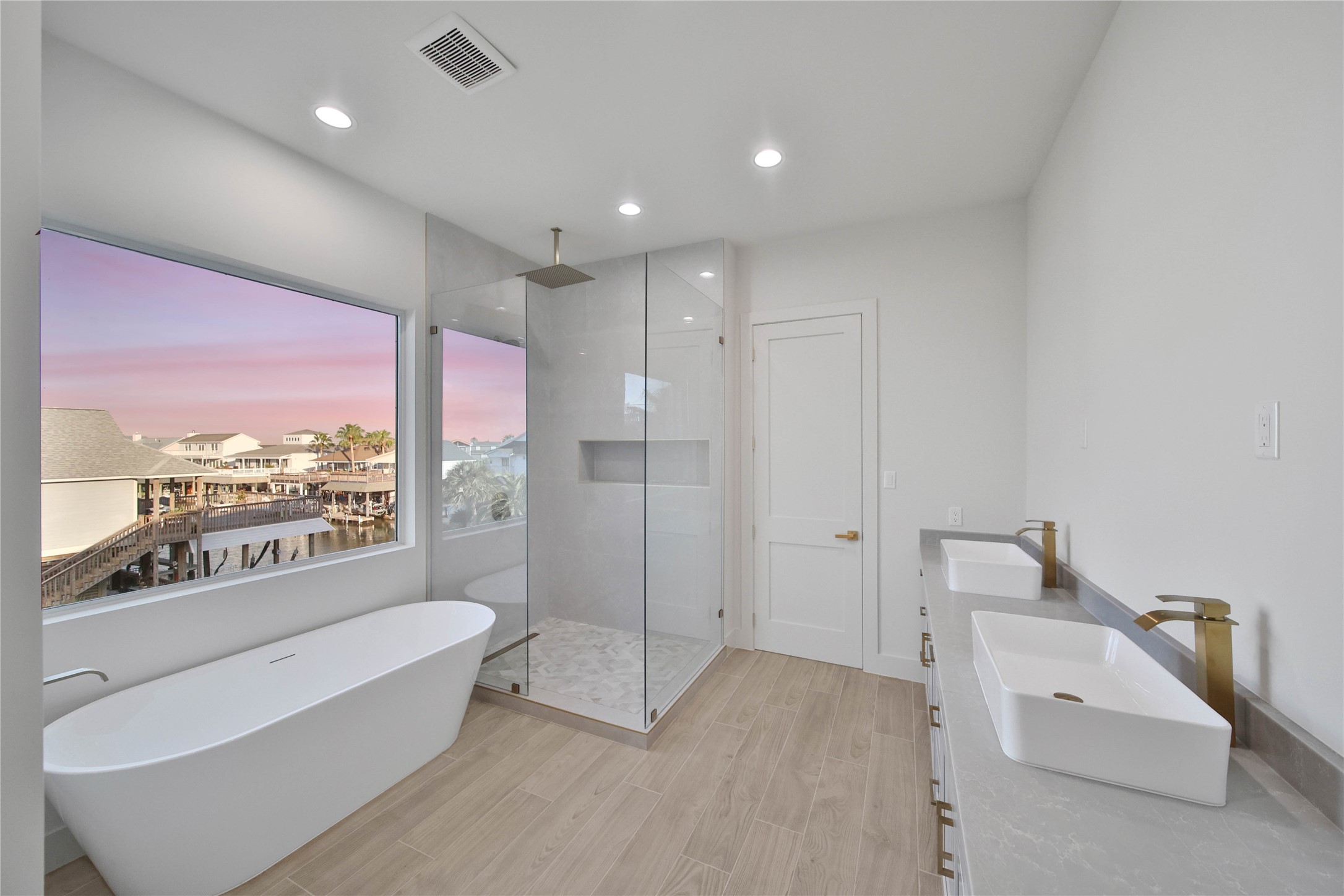 Spacious primary bathroom featuring dual sinks, a soaking tub, and separate shower.