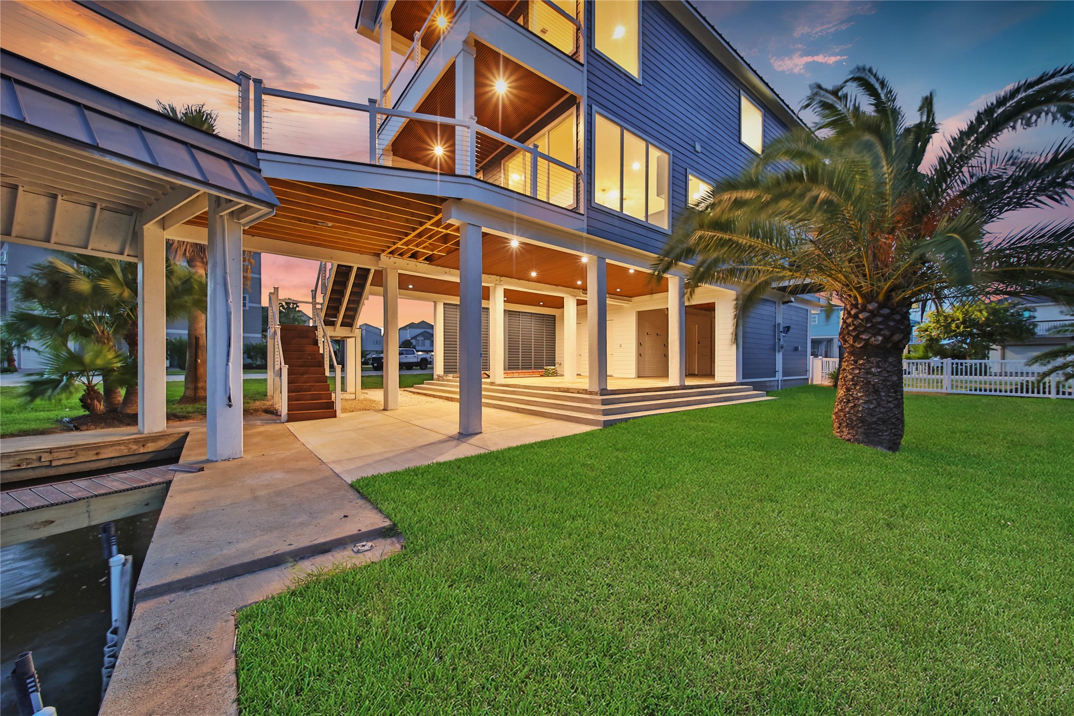 Rear view showcases the homes multiple outdoor living areas and expansive 12,000+ sqft waterfront lot.